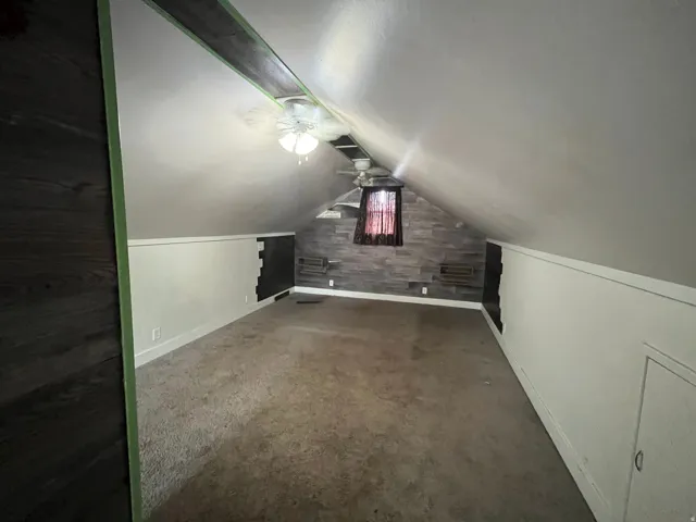Additional living space featuring a ceiling fan and dark colored carpet