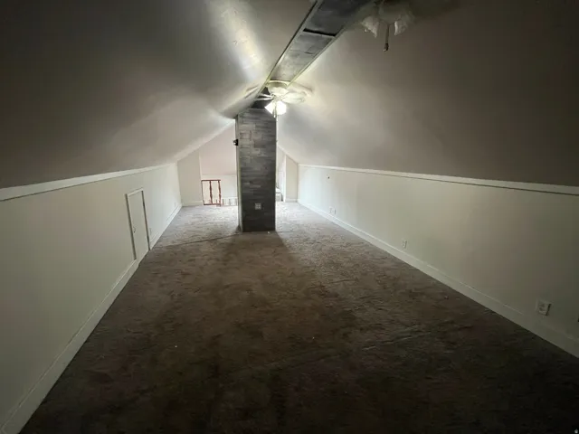 Additional living space featuring dark colored carpet and a ceiling fan