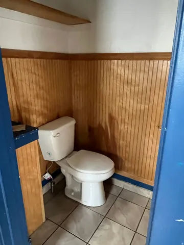 Bathroom with wooden walls, light tile patterned floors, and a wainscoted wall