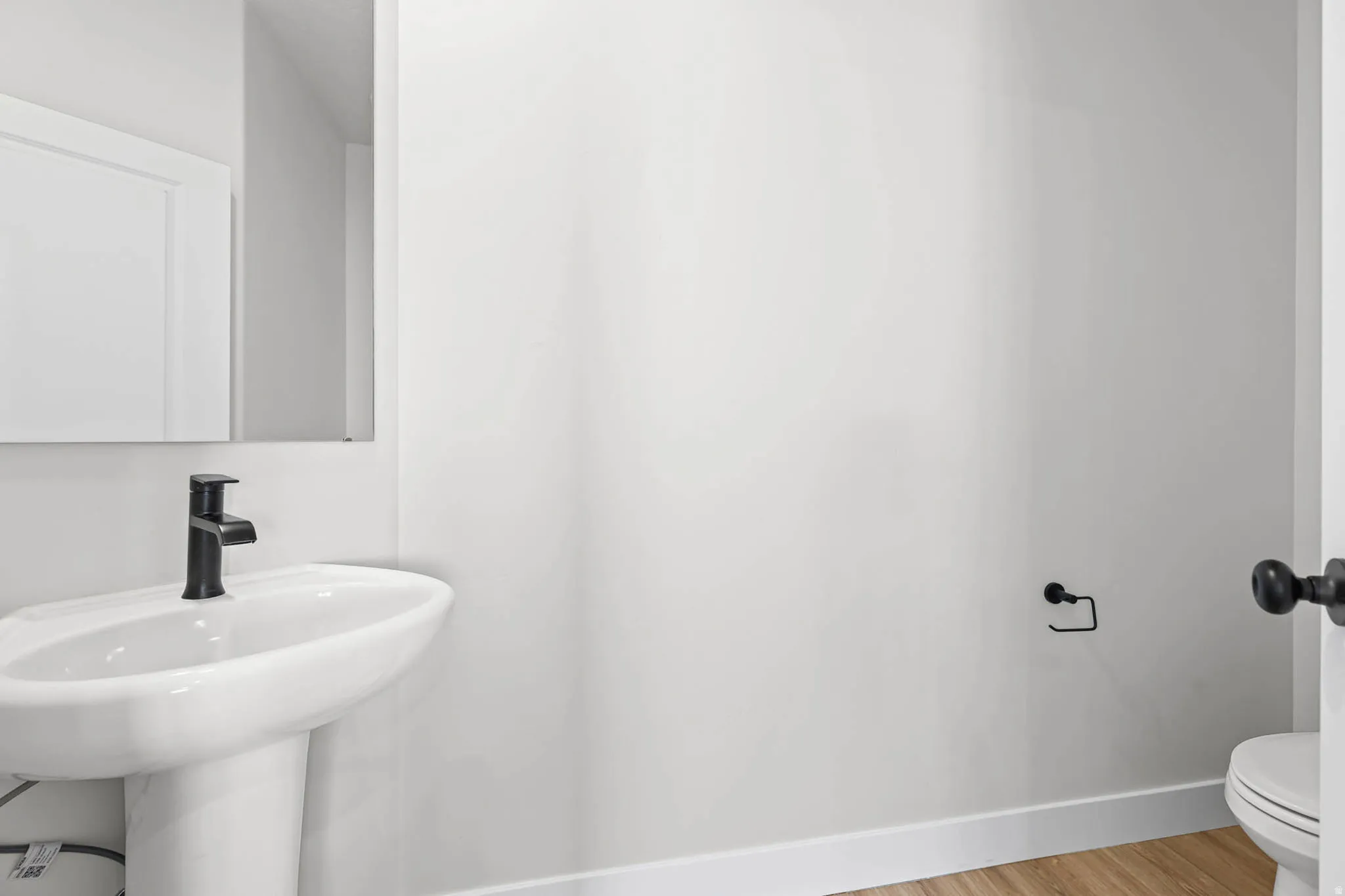 Half bathroom with toilet and light wood finished floors