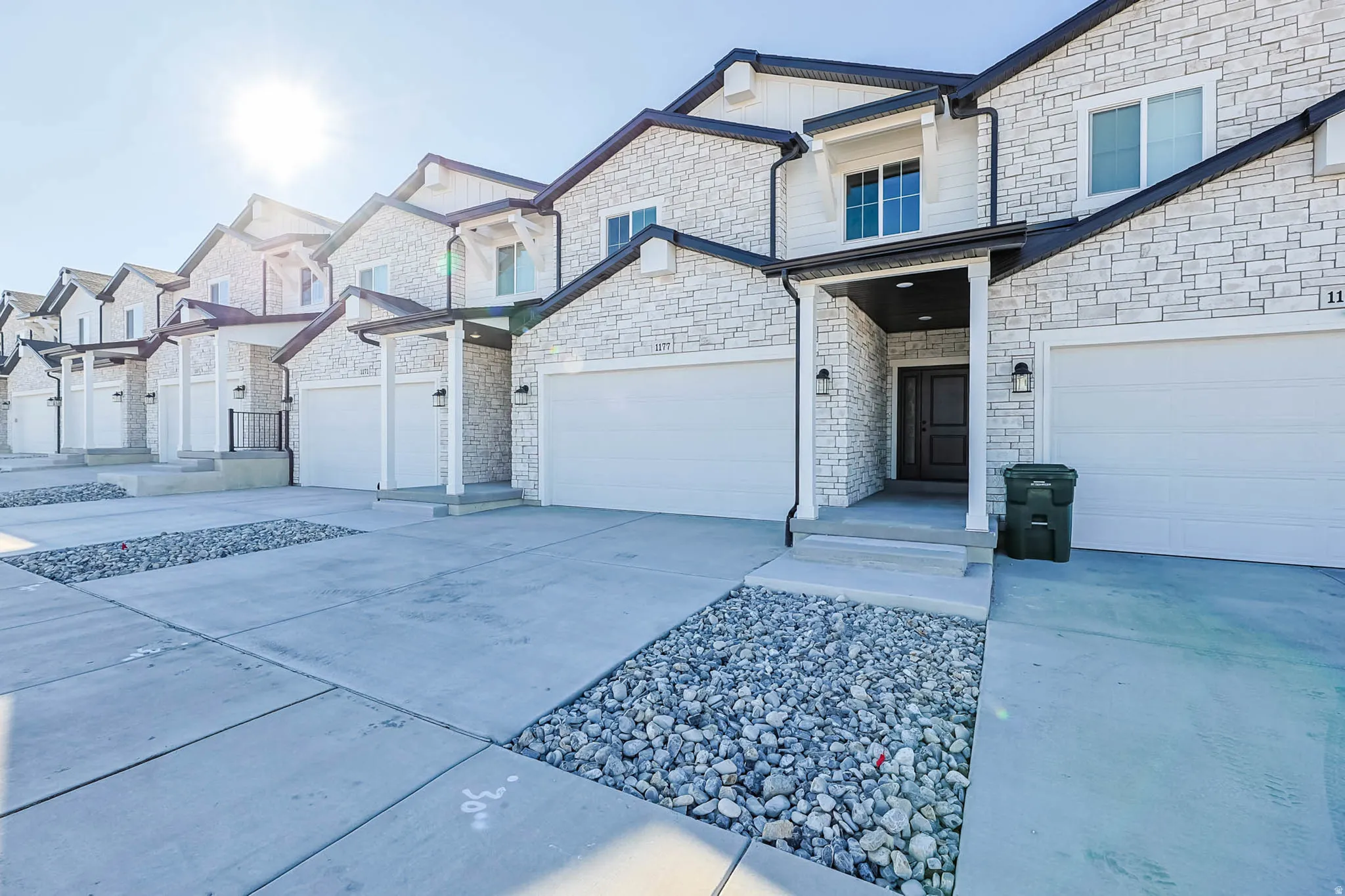 View of front of home with stone siding, concrete driveway, a residential view, and a garage