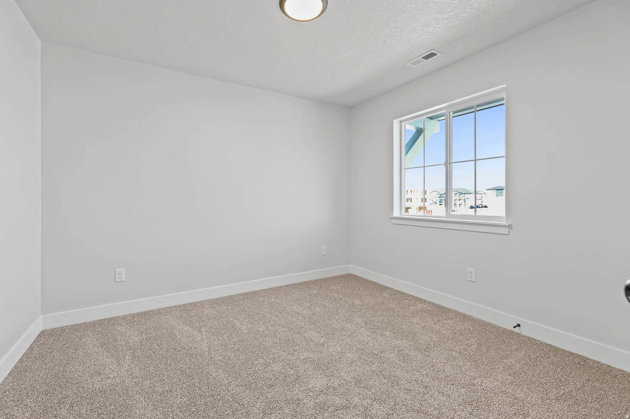 Empty room with carpet and a textured ceiling