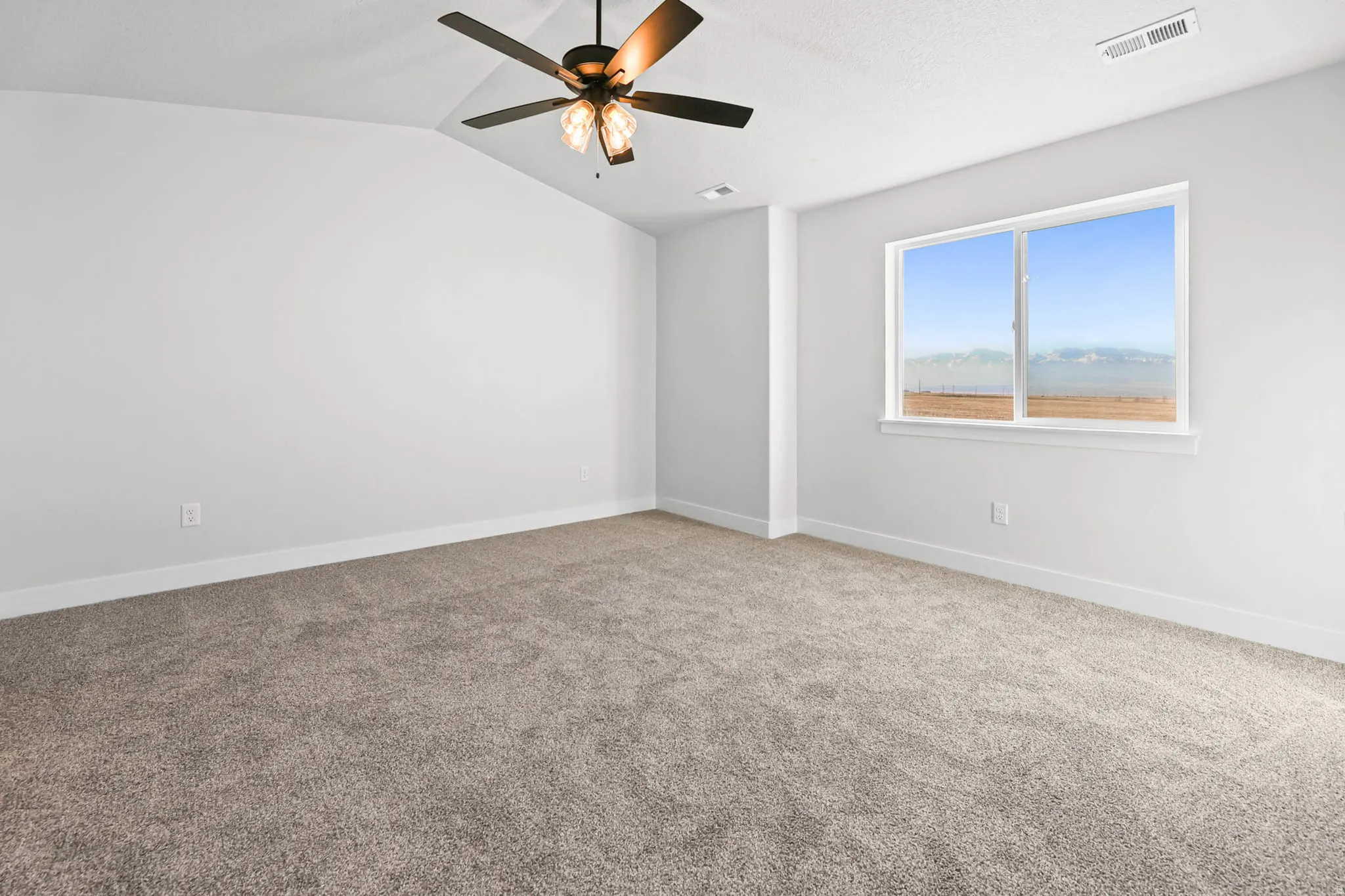 Carpeted empty room with lofted ceiling and ceiling fan