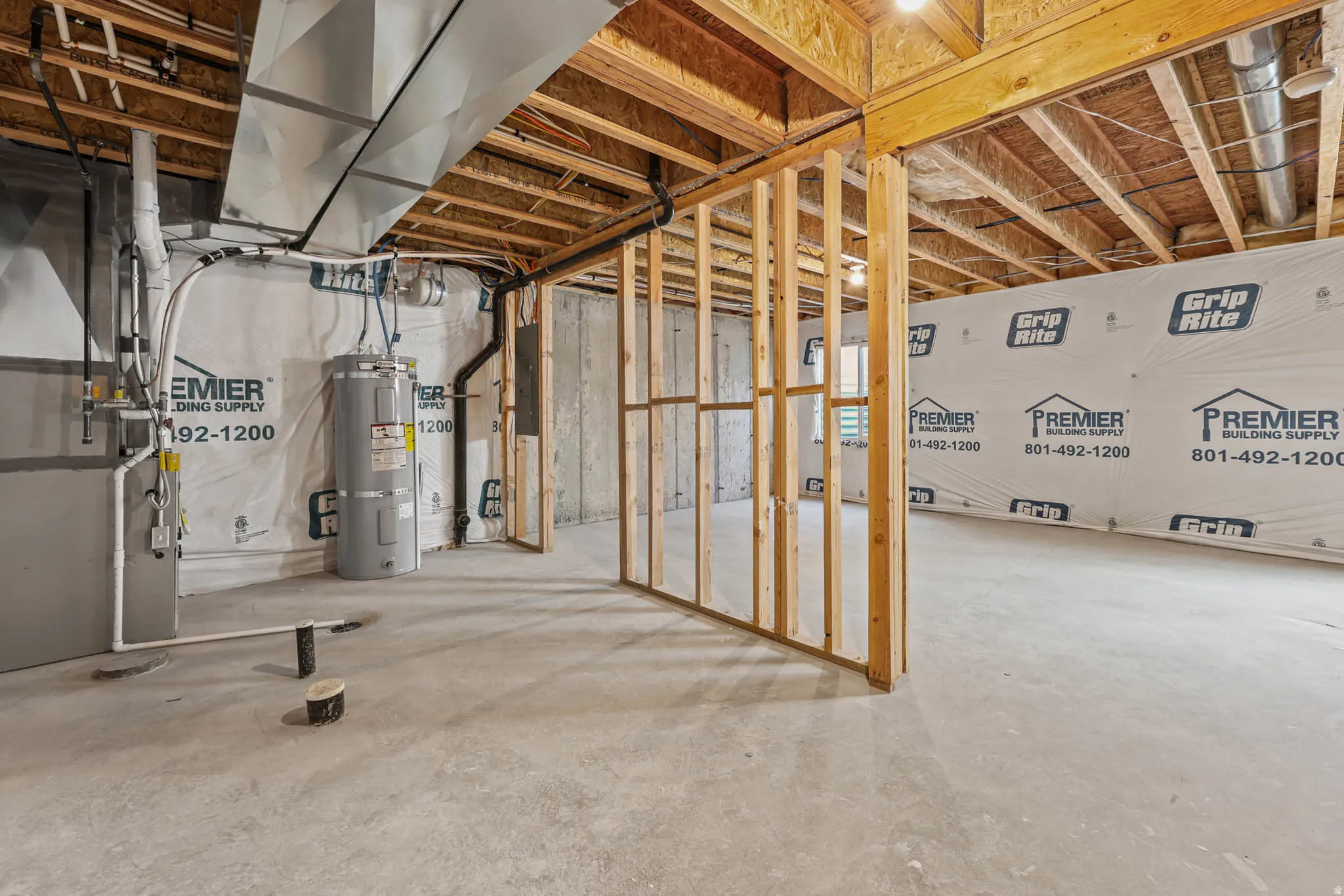 Unfinished basement featuring heating unit, secured water heater, and electric panel