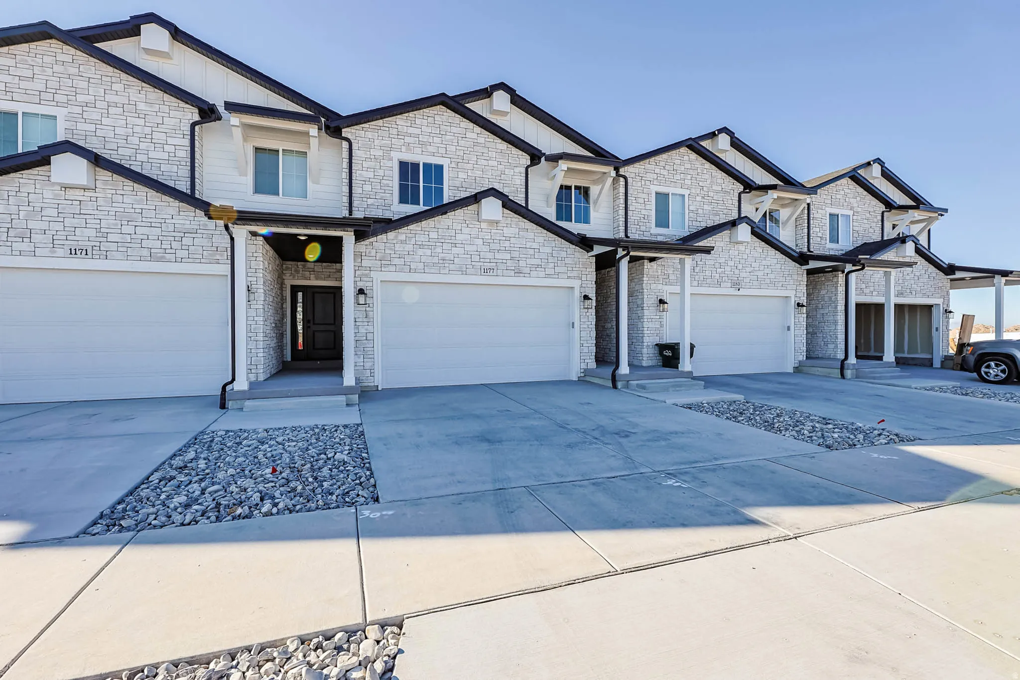 View of front of house featuring concrete driveway, stone siding, and board and batten siding