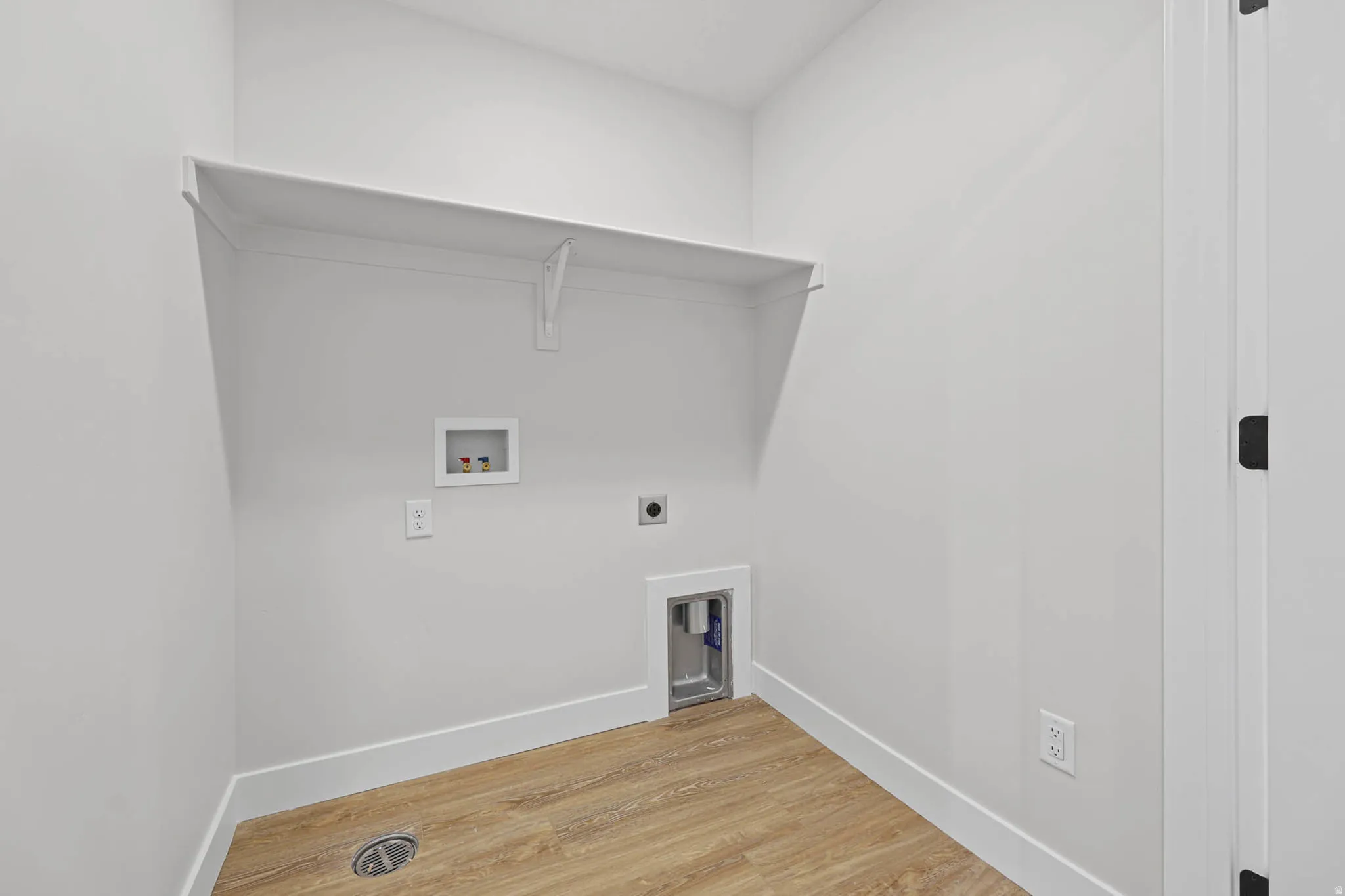 Laundry room with hookup for a washing machine, light wood-style floors, and hookup for an electric dryer