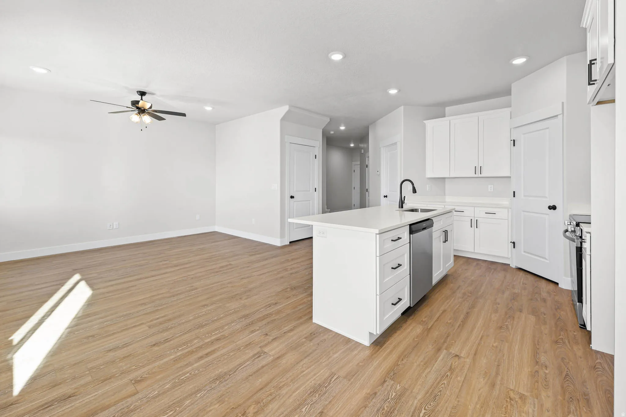 Kitchen featuring white cabinetry, a center island with sink, light wood-type flooring, recessed lighting, and a ceiling fan