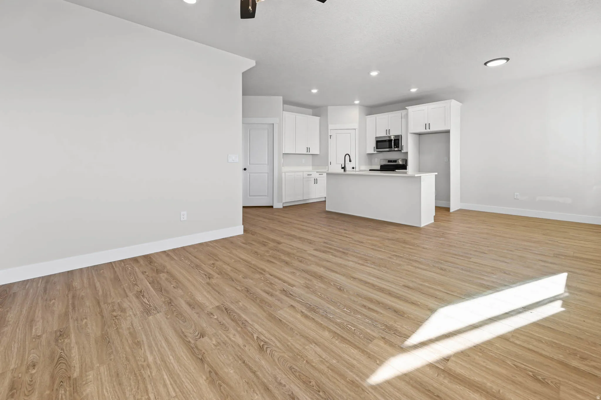 Unfurnished living room featuring light wood-style floors, ceiling fan, and recessed lighting