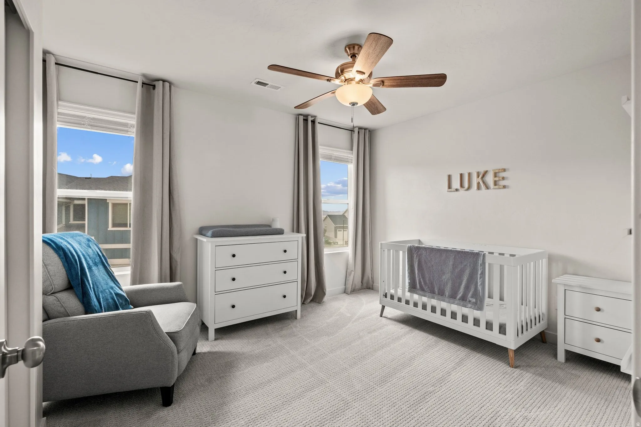 Bedroom featuring a crib, light carpet, and ceiling fan
