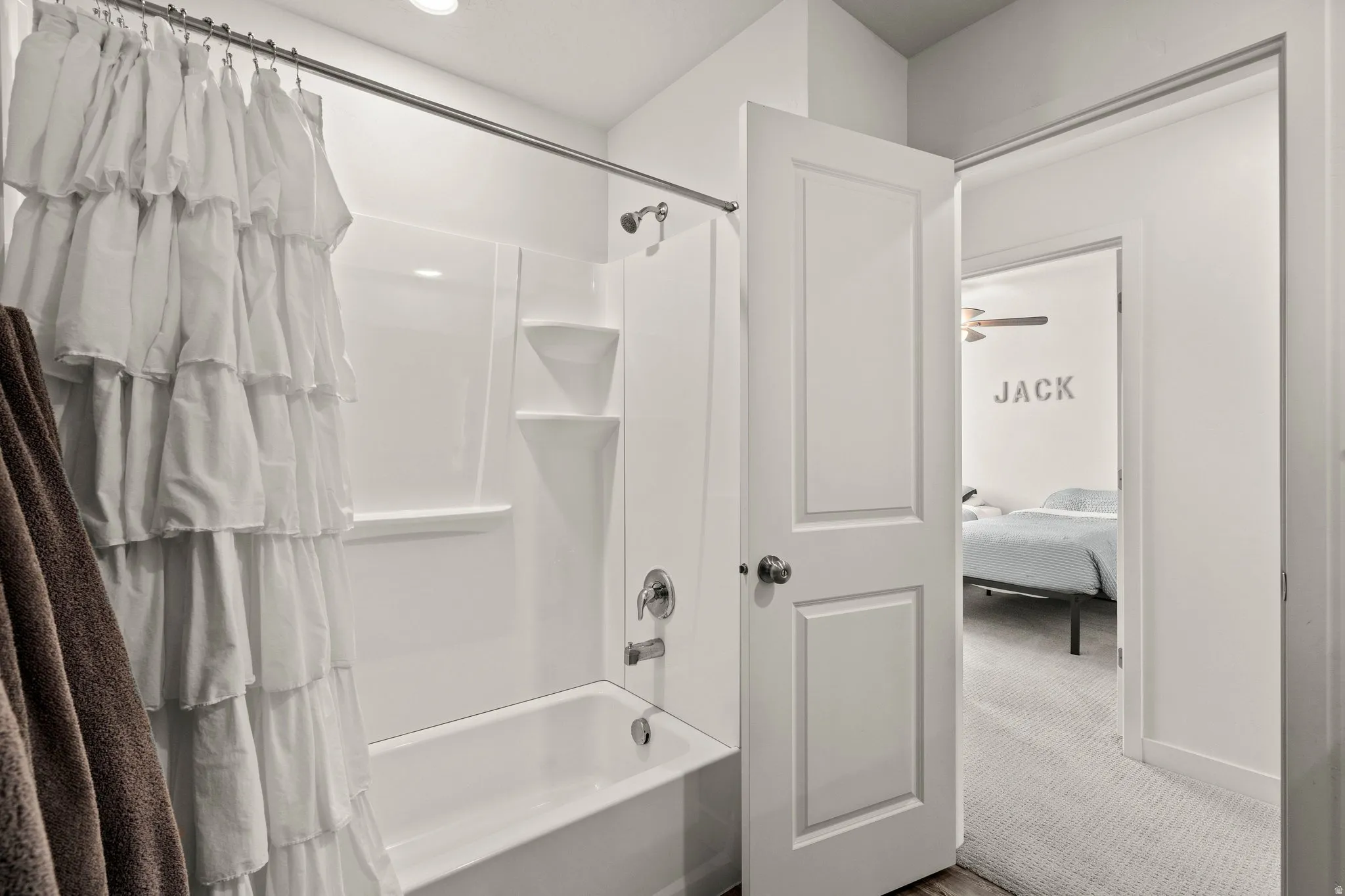 Ensuite bathroom featuring shower / tub combo with curtain and light carpet