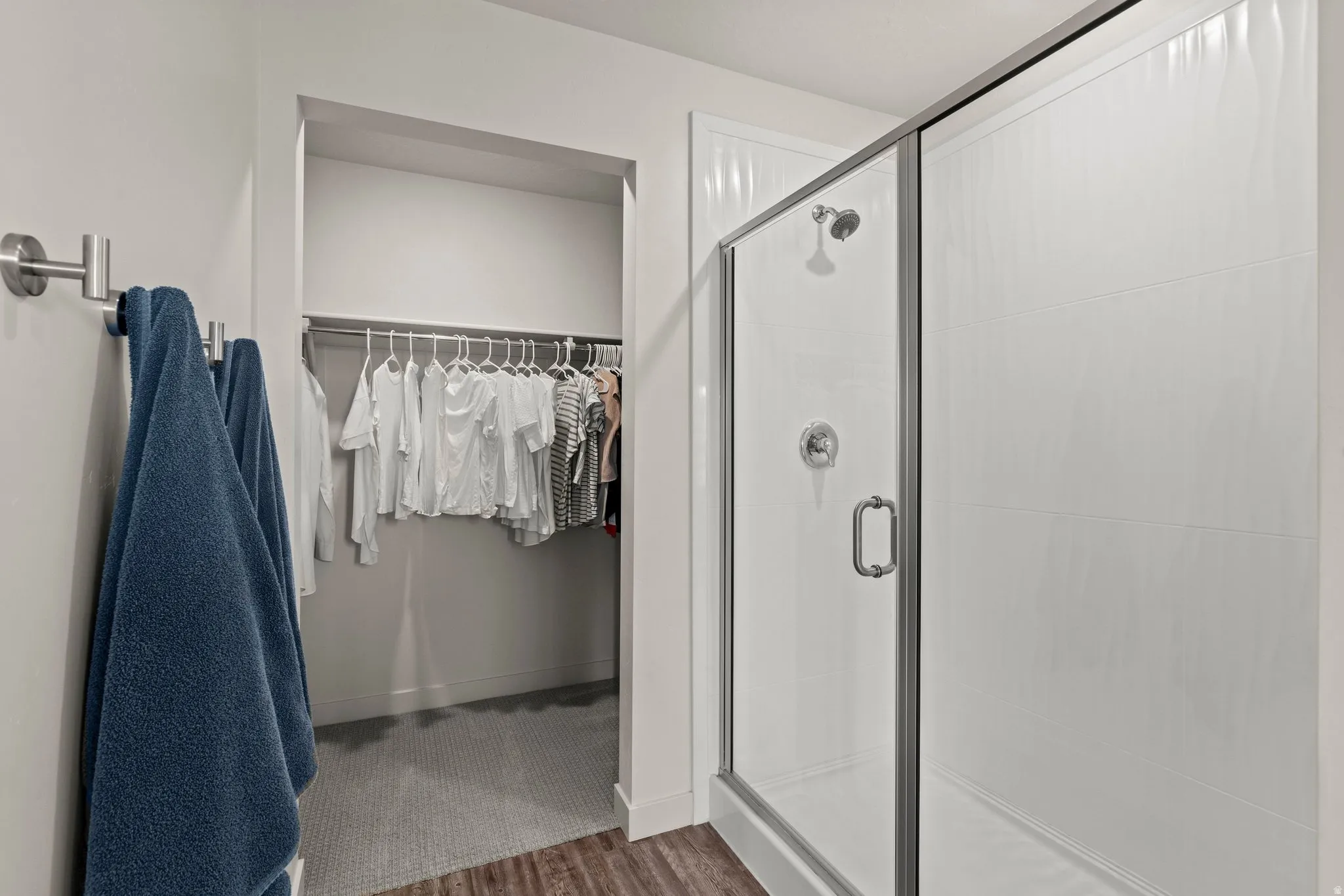 Full bathroom with a spacious closet, a stall shower, and dark wood-type flooring