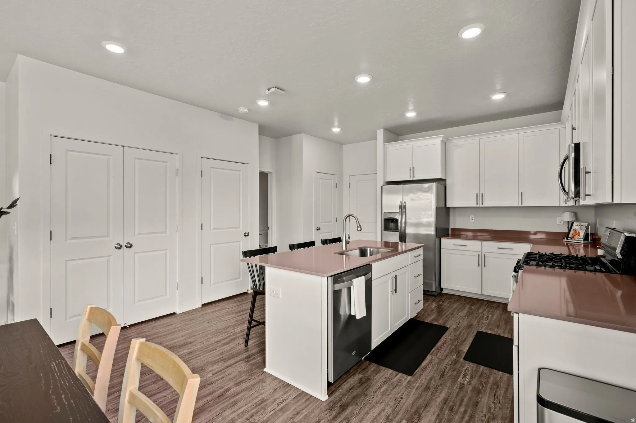 Kitchen with white cabinets, a breakfast bar, dark wood-type flooring, and recessed lighting