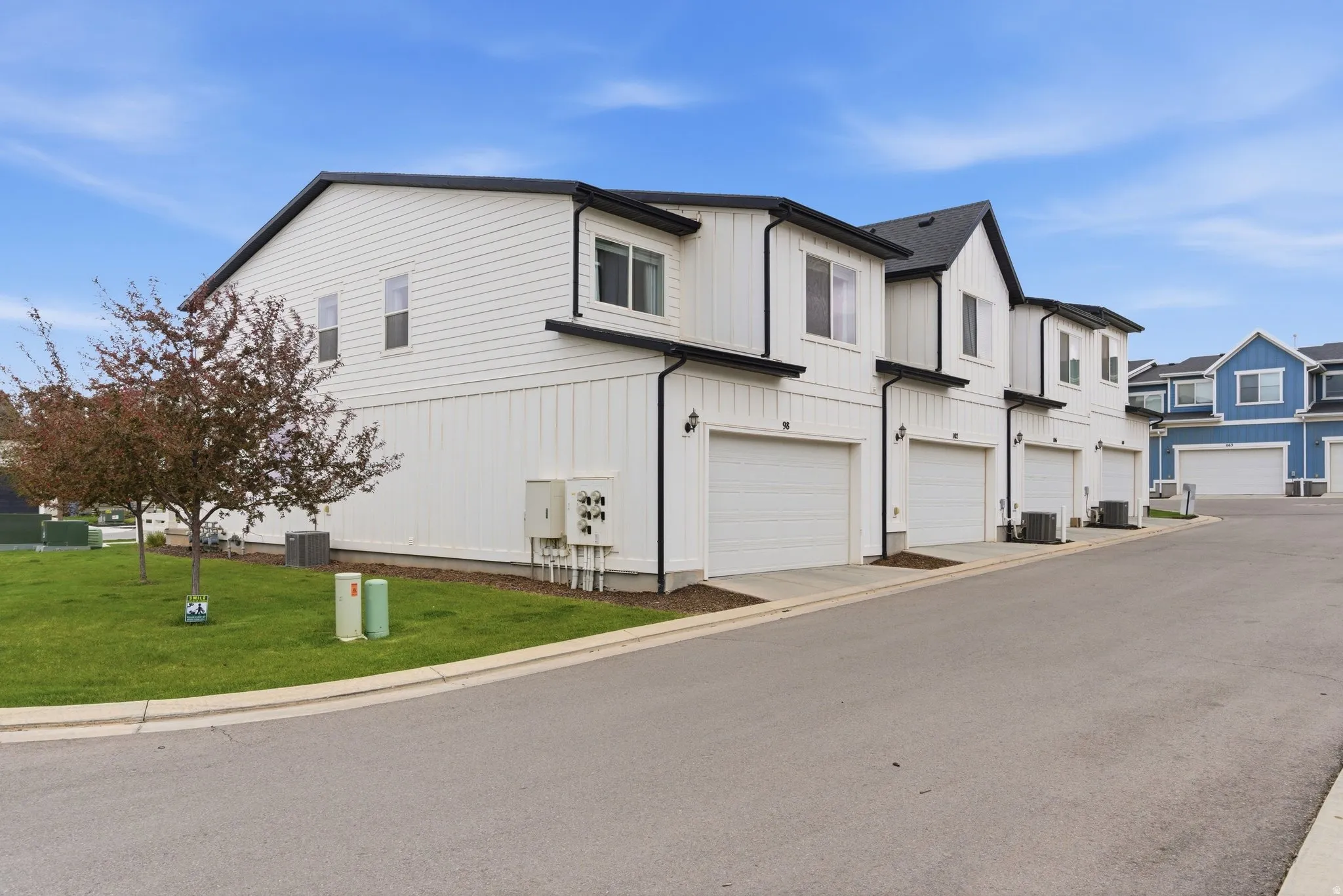 View of side of property featuring a lawn, an attached garage, a residential view, and board and batten siding