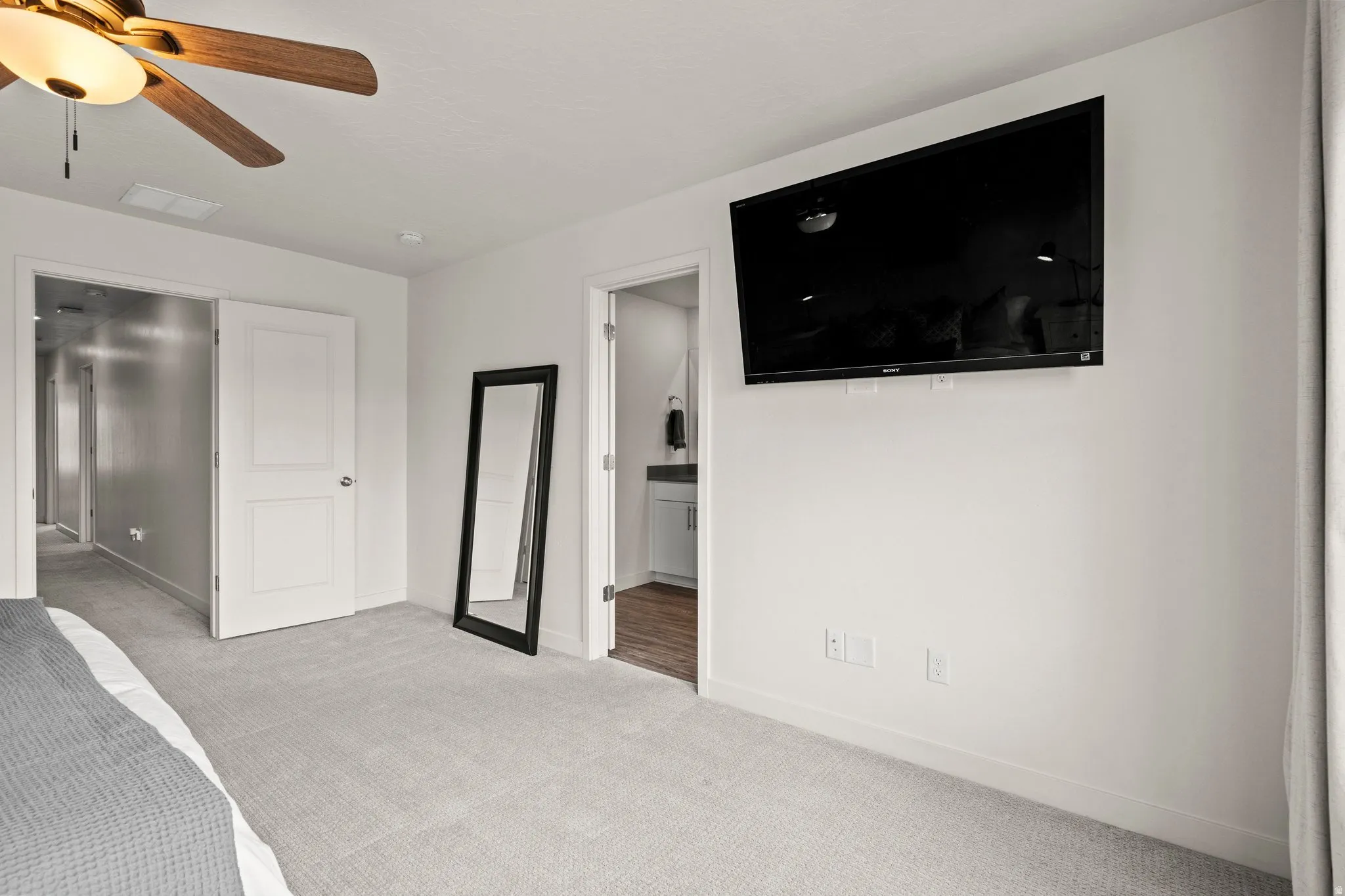 Unfurnished bedroom featuring light colored carpet, connected bathroom, and a ceiling fan