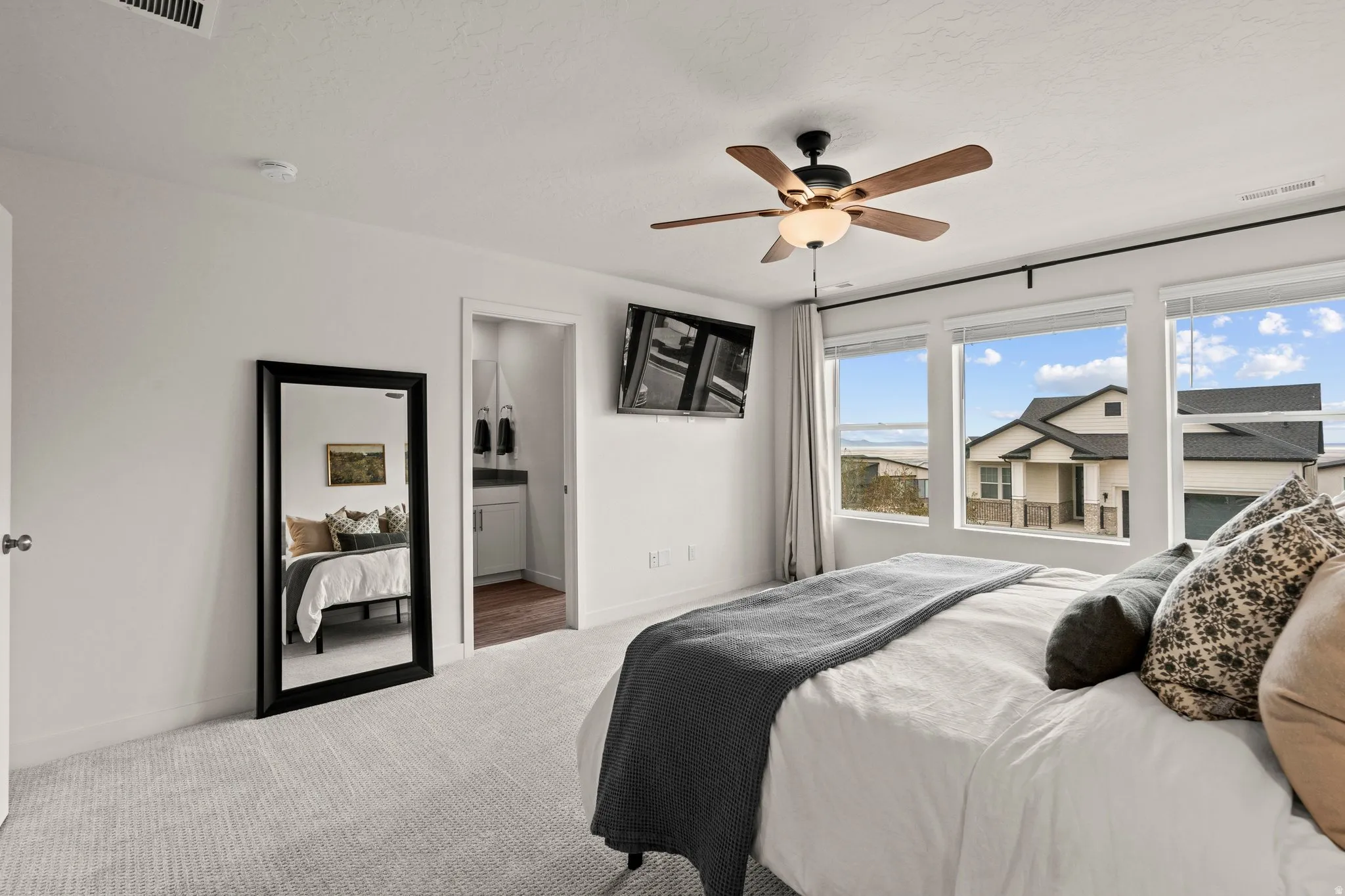 Carpeted bedroom with a ceiling fan and connected bathroom