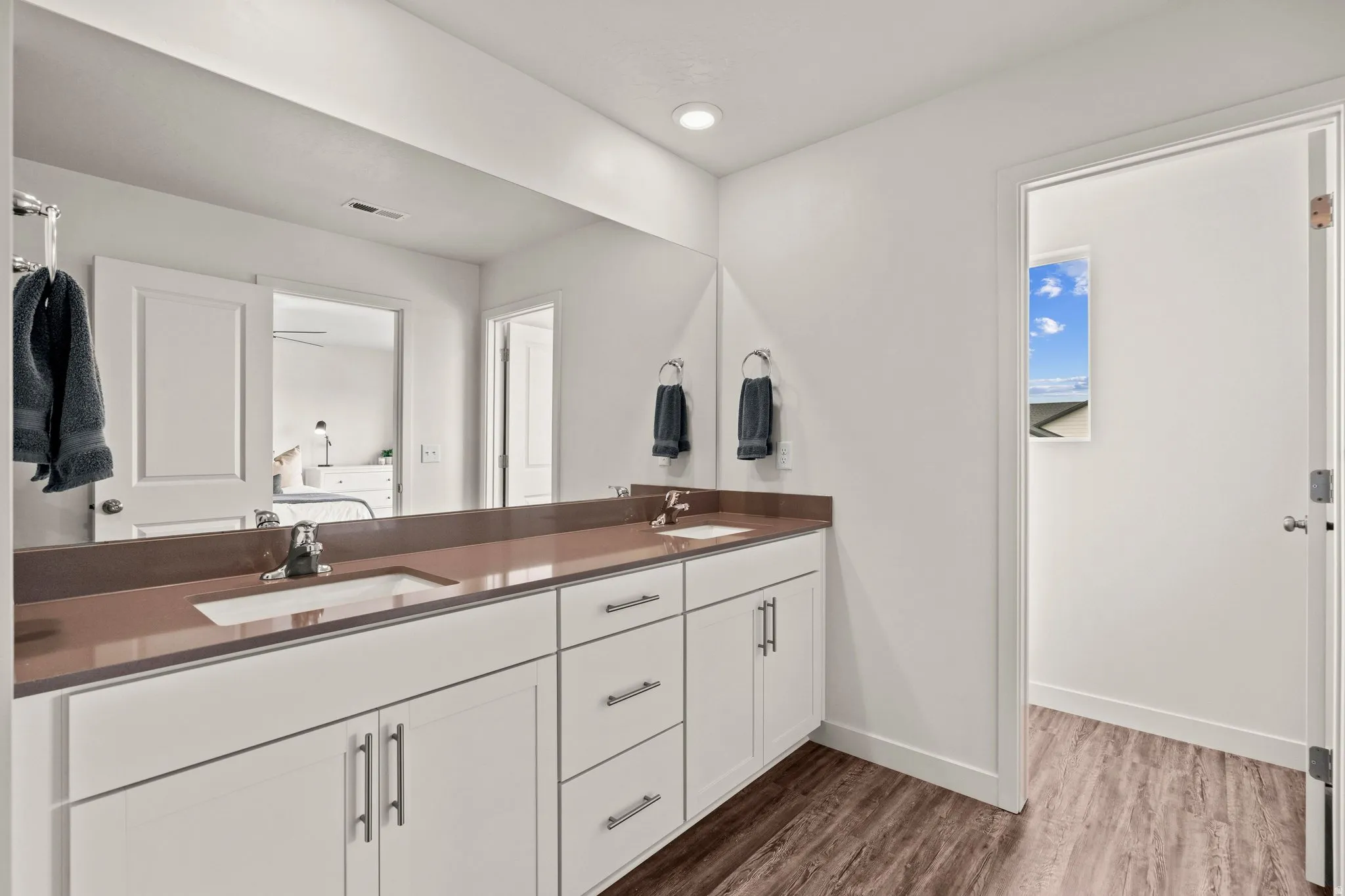 Full bath with double vanity, dark wood-style floors, and recessed lighting