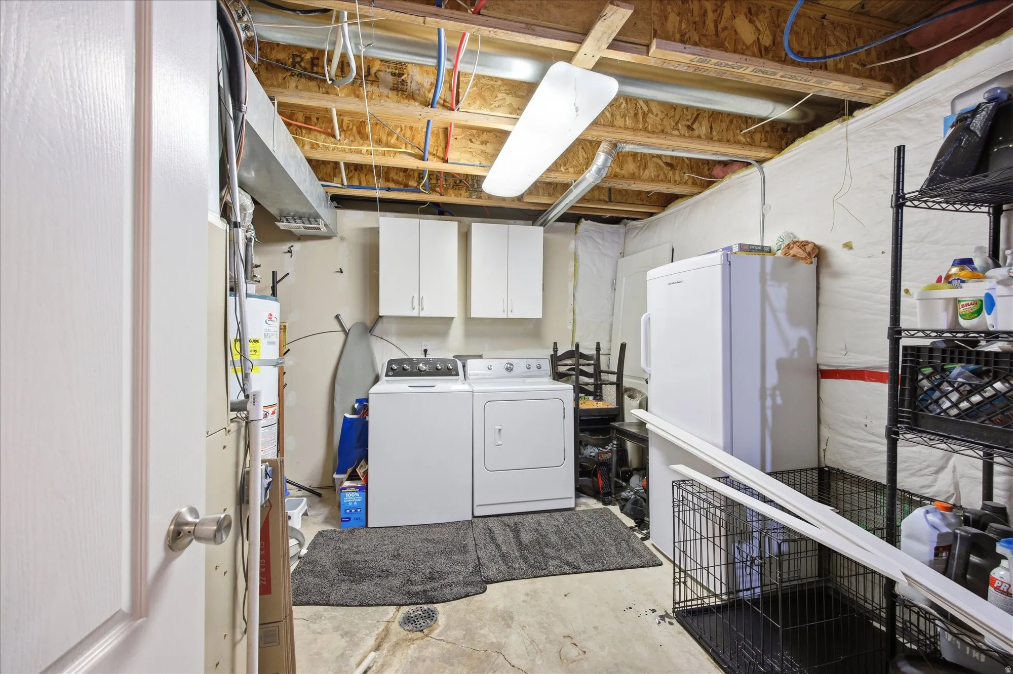 Laundry area with concrete floors, washing machine and clothes dryer, cabinet space, and gas water heater
