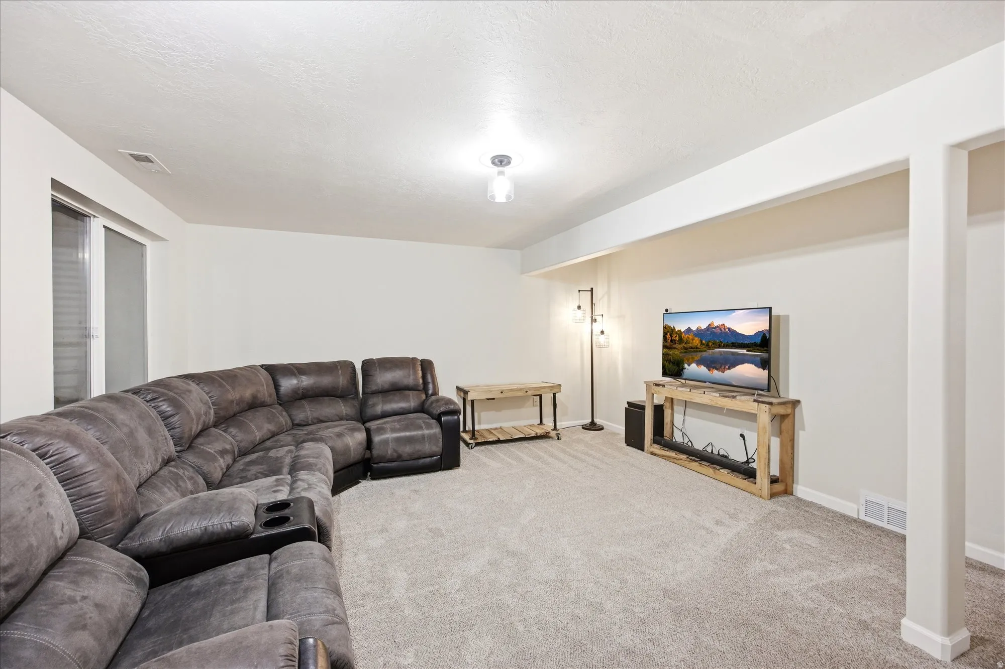 Living area featuring light colored carpet and a textured ceiling