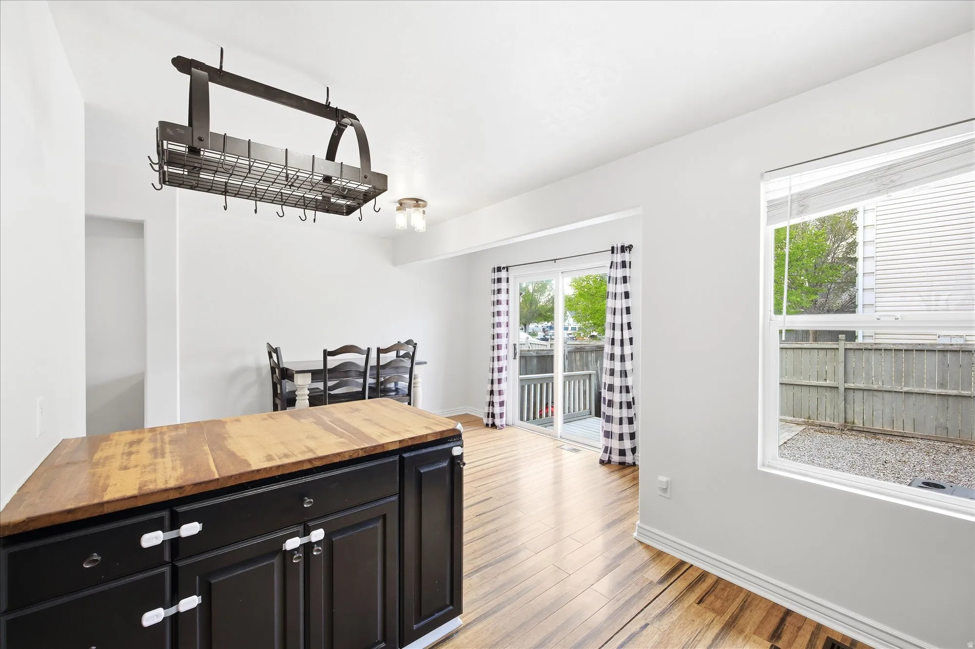 Kitchen with dark cabinets, wooden counters, and light wood-style floors