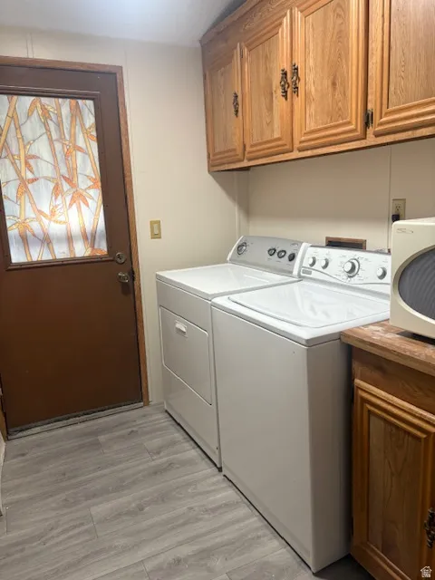 Laundry area featuring cabinet space, light wood finished floors, and washing machine and clothes dryer