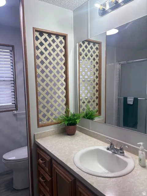 Full bath with a shower stall, vanity, and a textured ceiling
