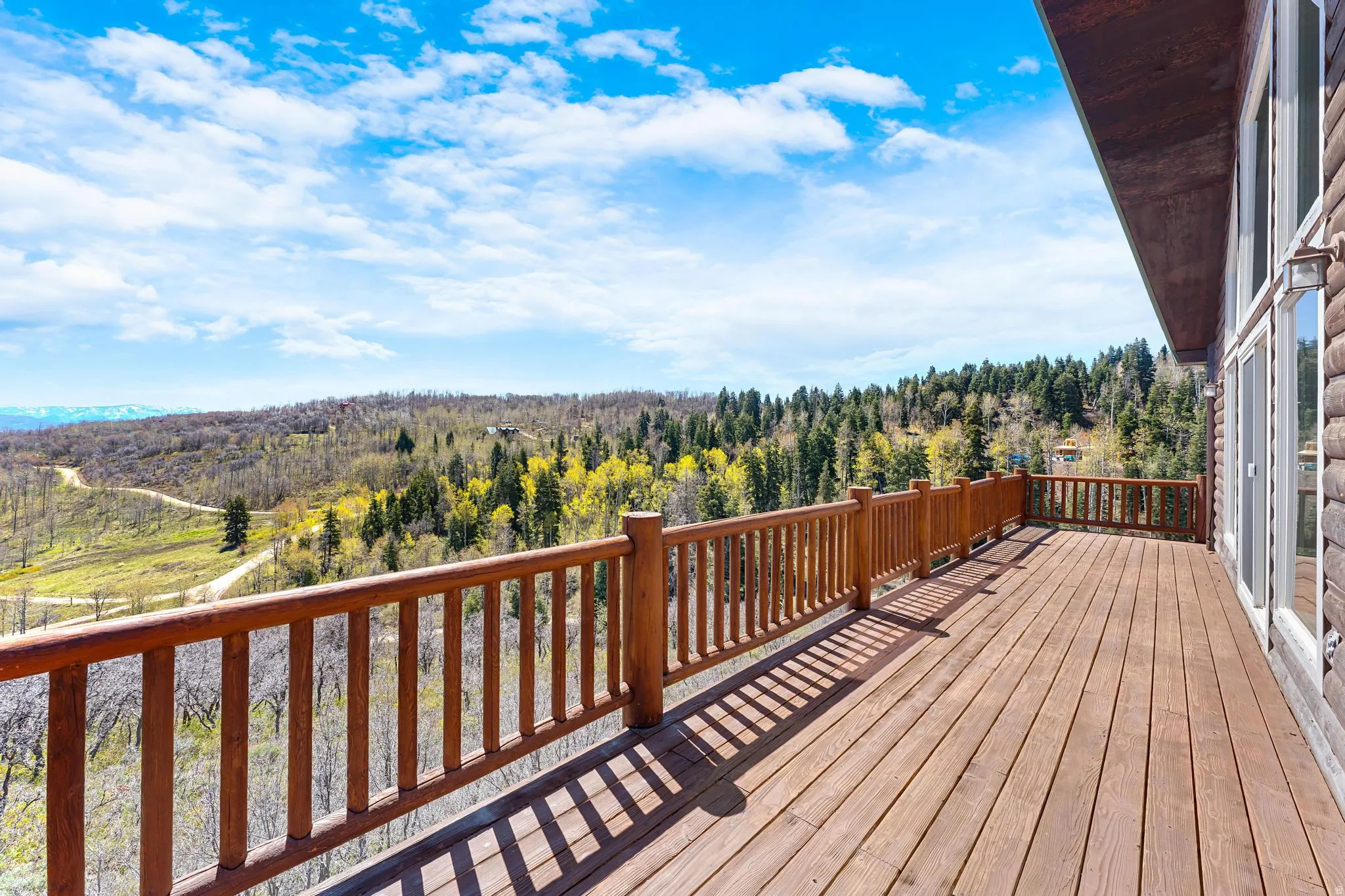 Expansive wood deck with a matching wood railing, offering sweeping mountain and forest scenery