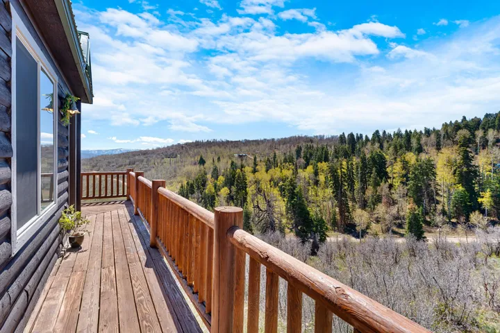 Expansive wood-plank deck with natural wood railings, offering elevated perspectives of the surrounding forest and distant mountains