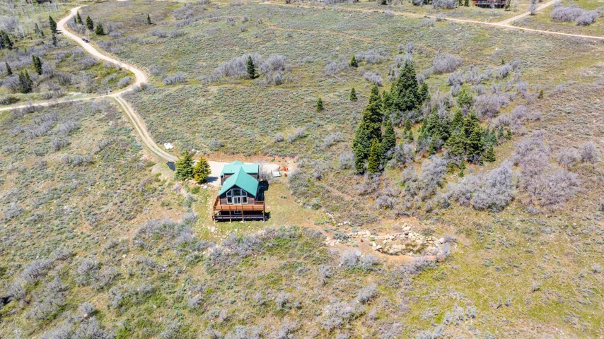 Wood-sided A-frame cabin featuring a green metal roof and a full-width wood deck