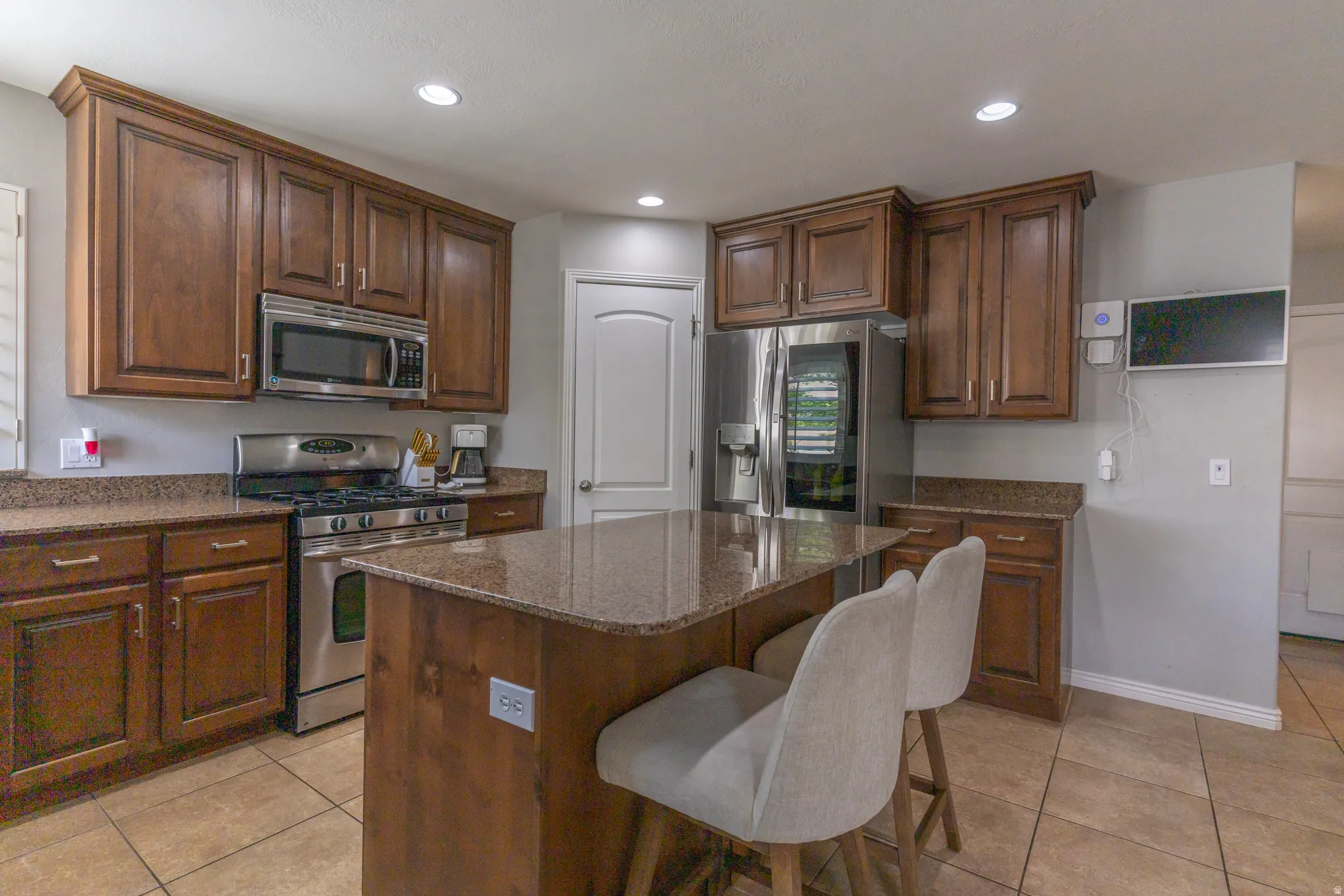 Kitchen with stainless steel appliances, dark stone counters, light tile patterned floors, and recessed lighting