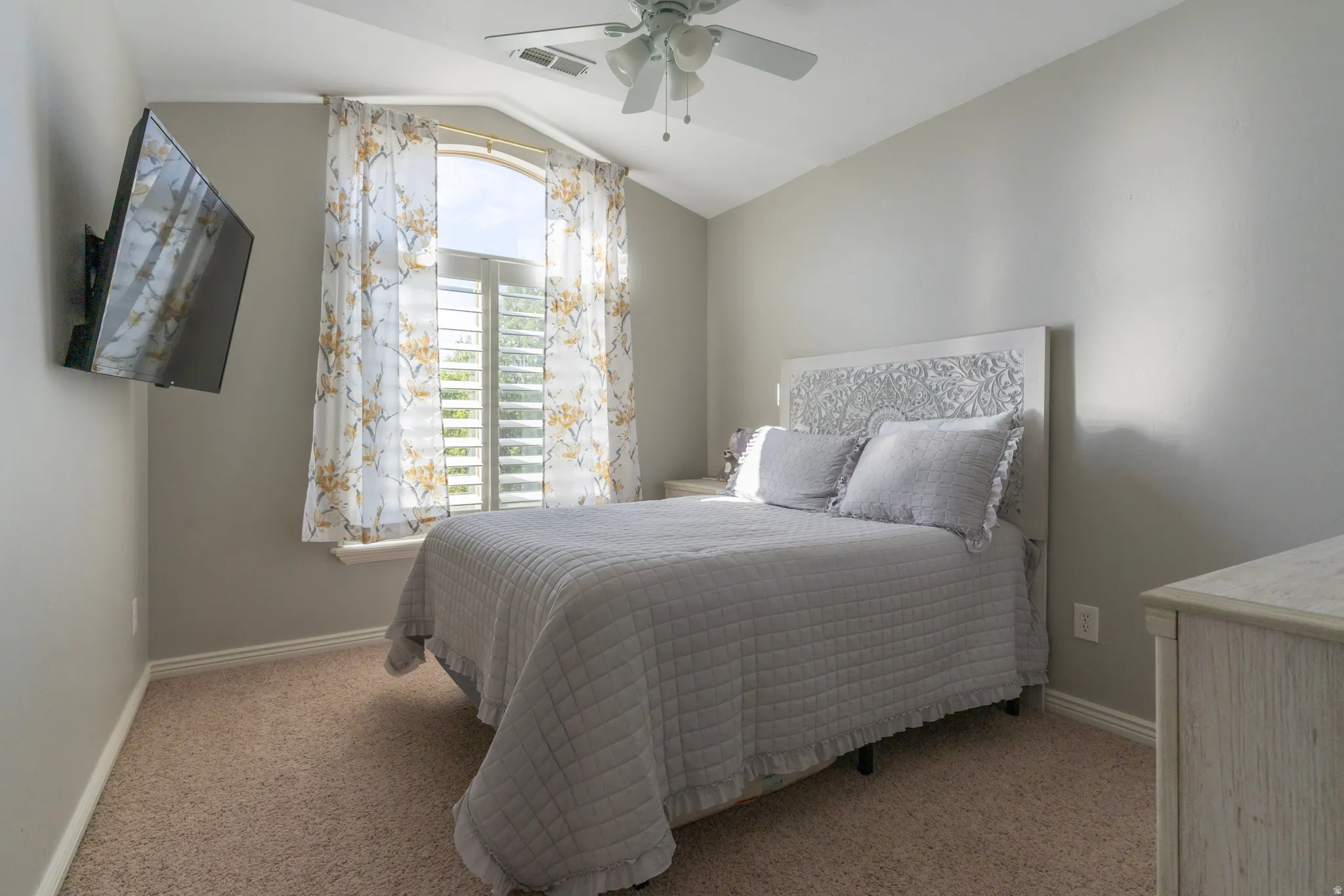 Bedroom with lofted ceiling, light carpet, and a ceiling fan