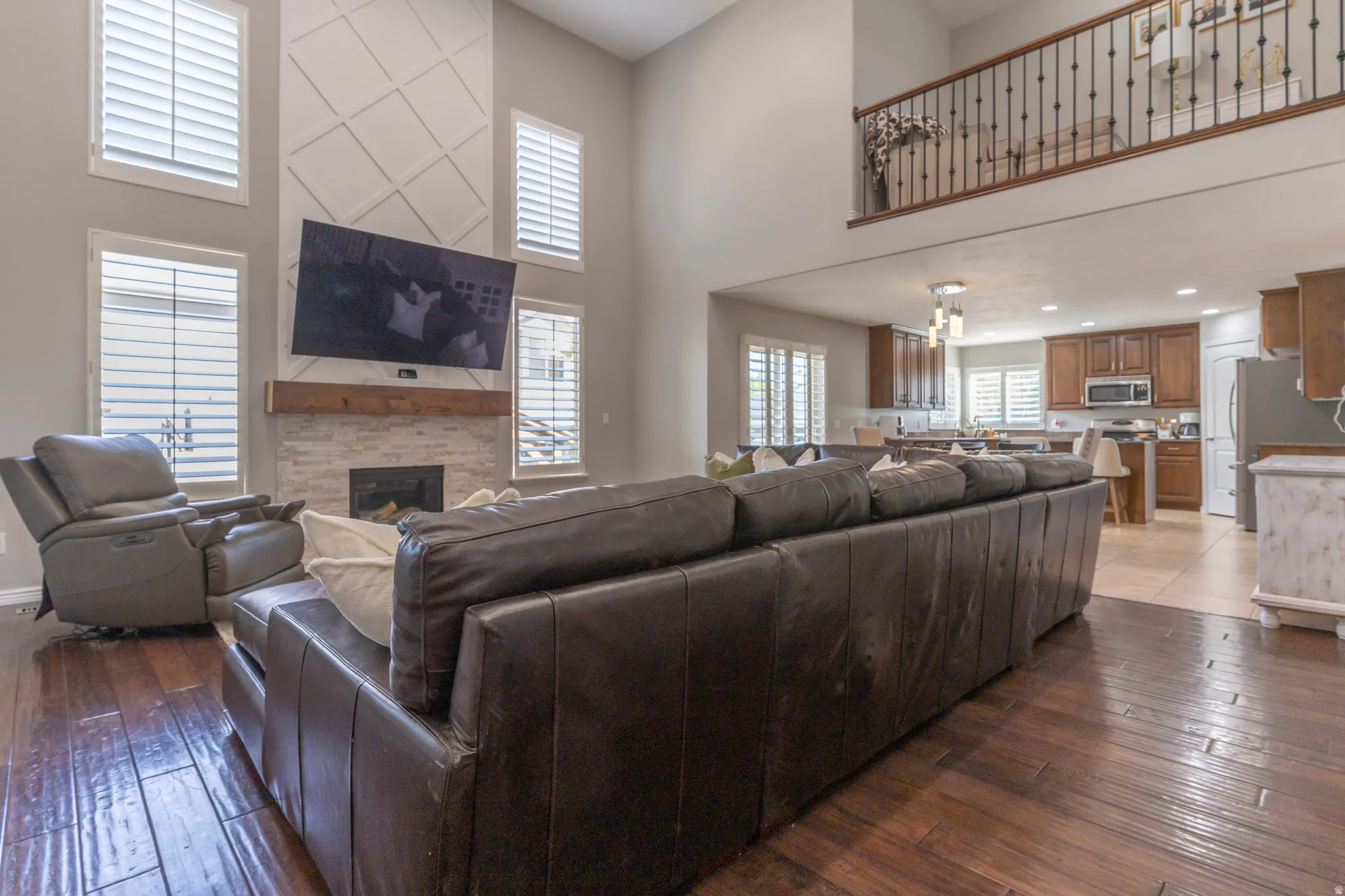 Living area with a high ceiling, dark wood-style flooring, a glass covered fireplace, and recessed lighting