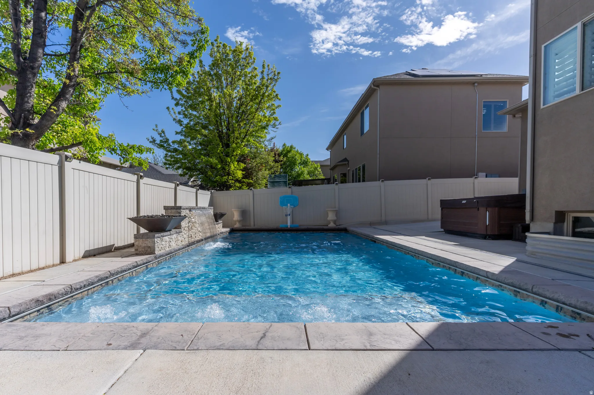 View of swimming pool with a fenced backyard, a hot tub, and patio surround
