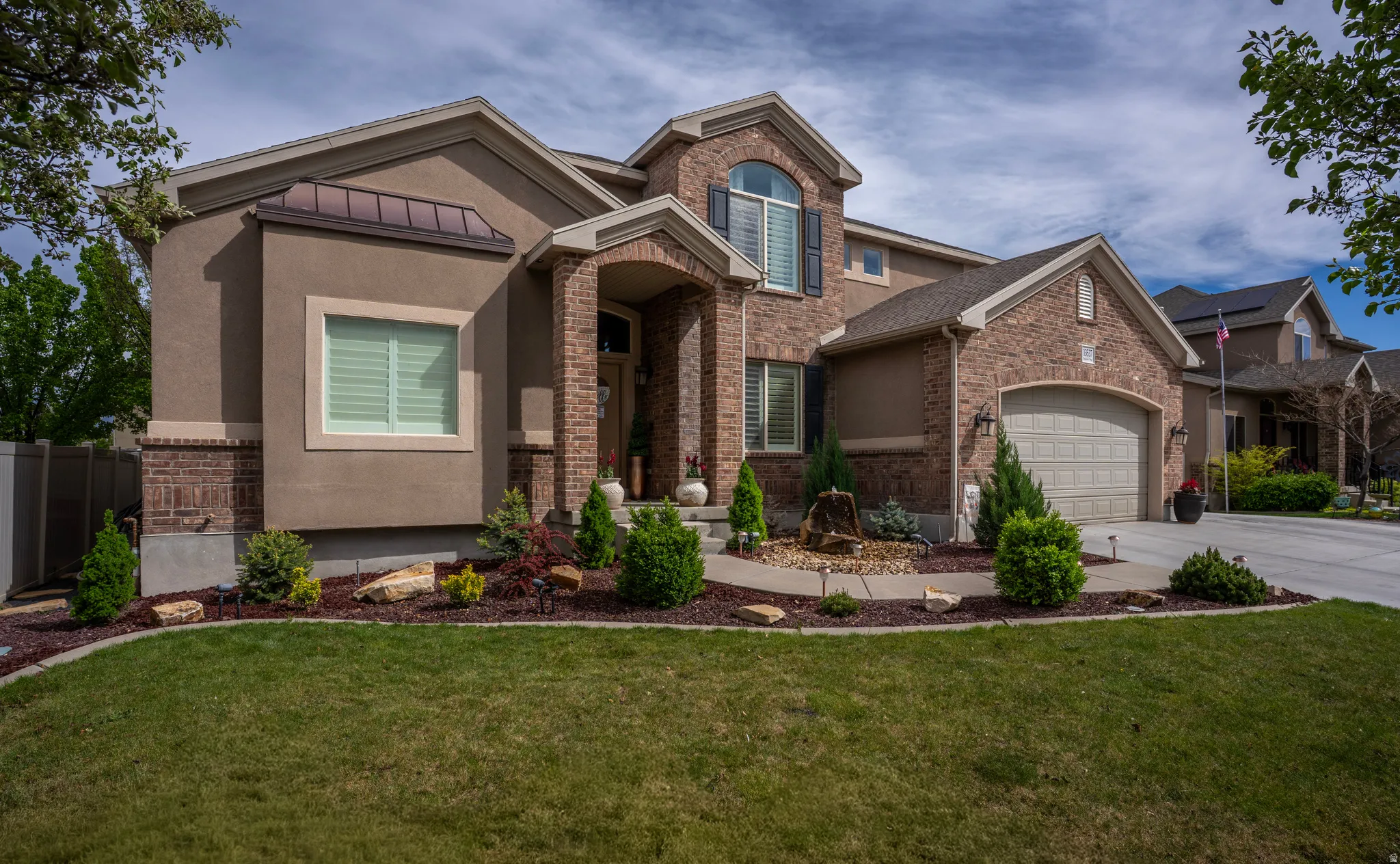 View of front facade with brick siding, a garage, concrete driveway, and stucco siding