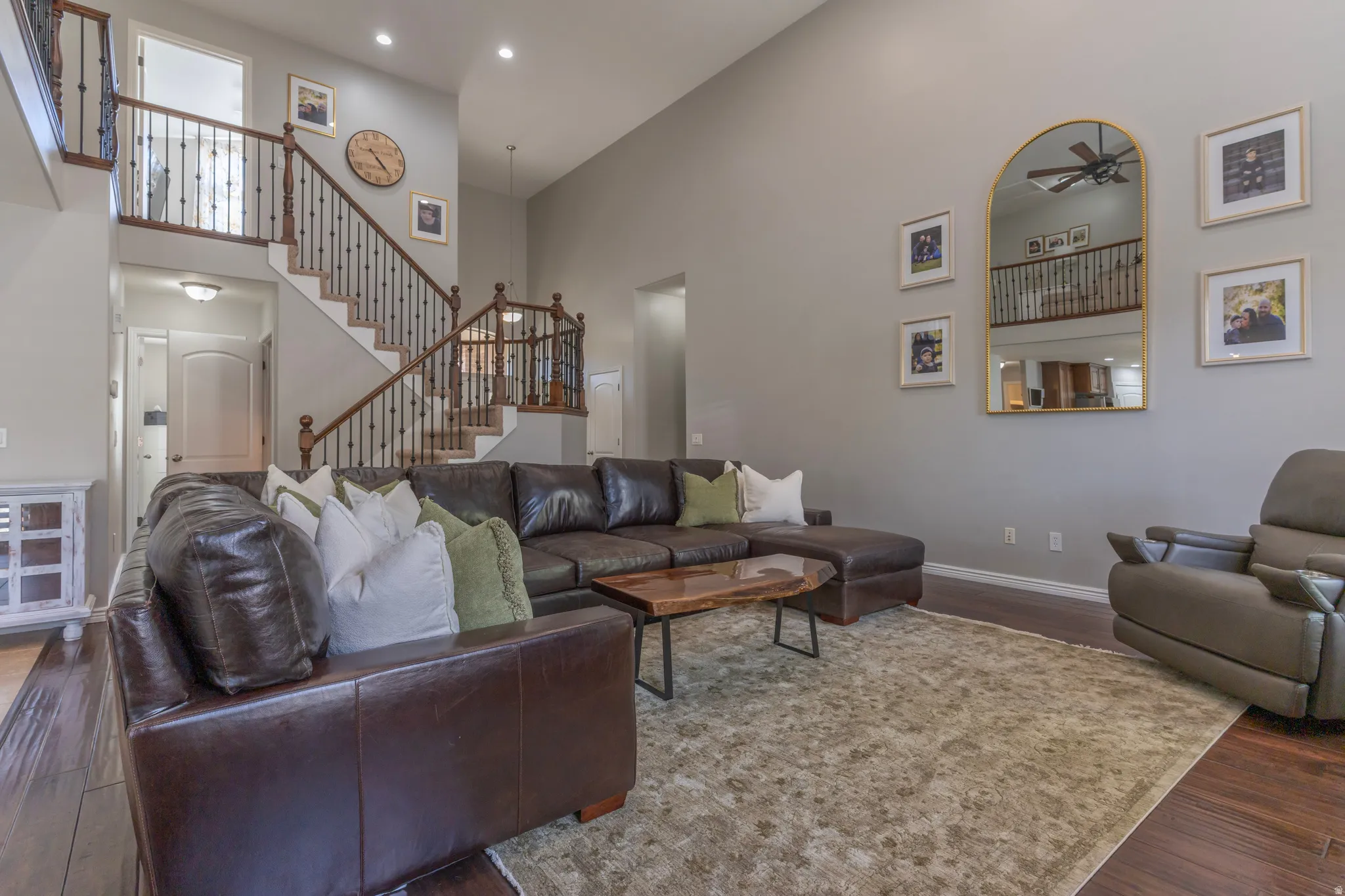Living area with a high ceiling, wood finished floors, a ceiling fan, and recessed lighting