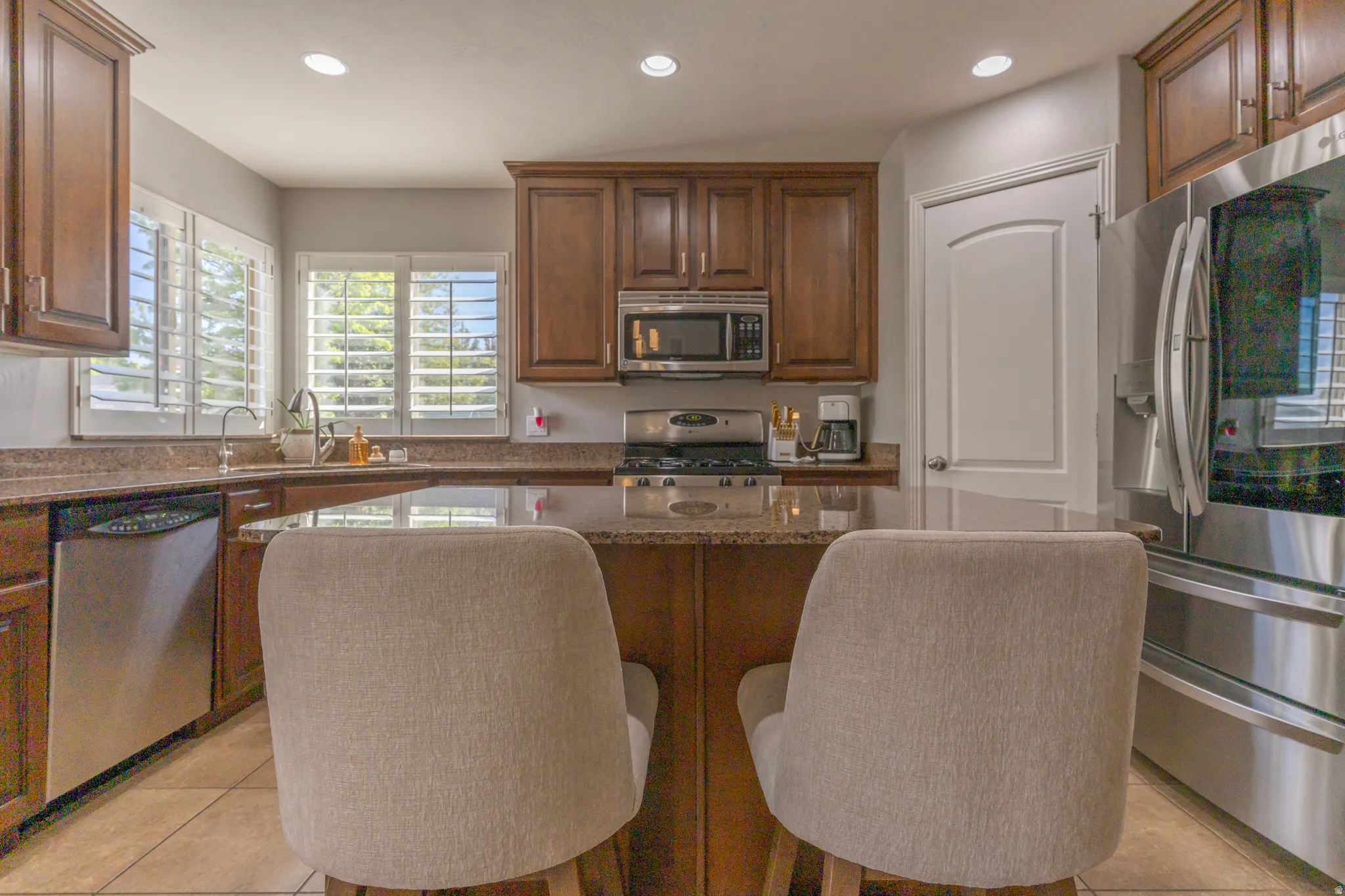 Kitchen featuring stainless steel appliances, recessed lighting, a center island, light tile patterned floors, and dark stone counters