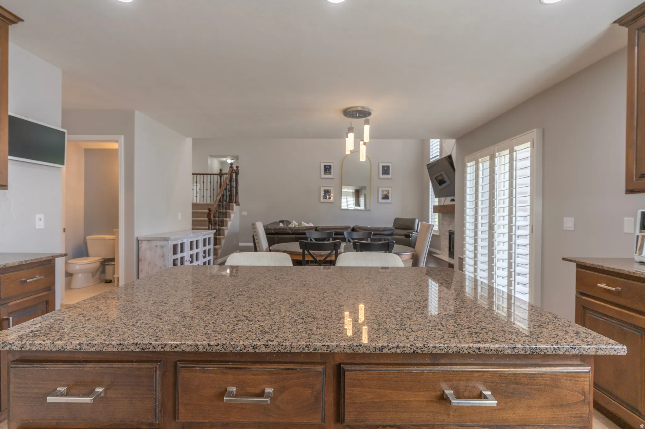 Kitchen with light stone countertops, open floor plan, wood finish cabinetry, and a kitchen island