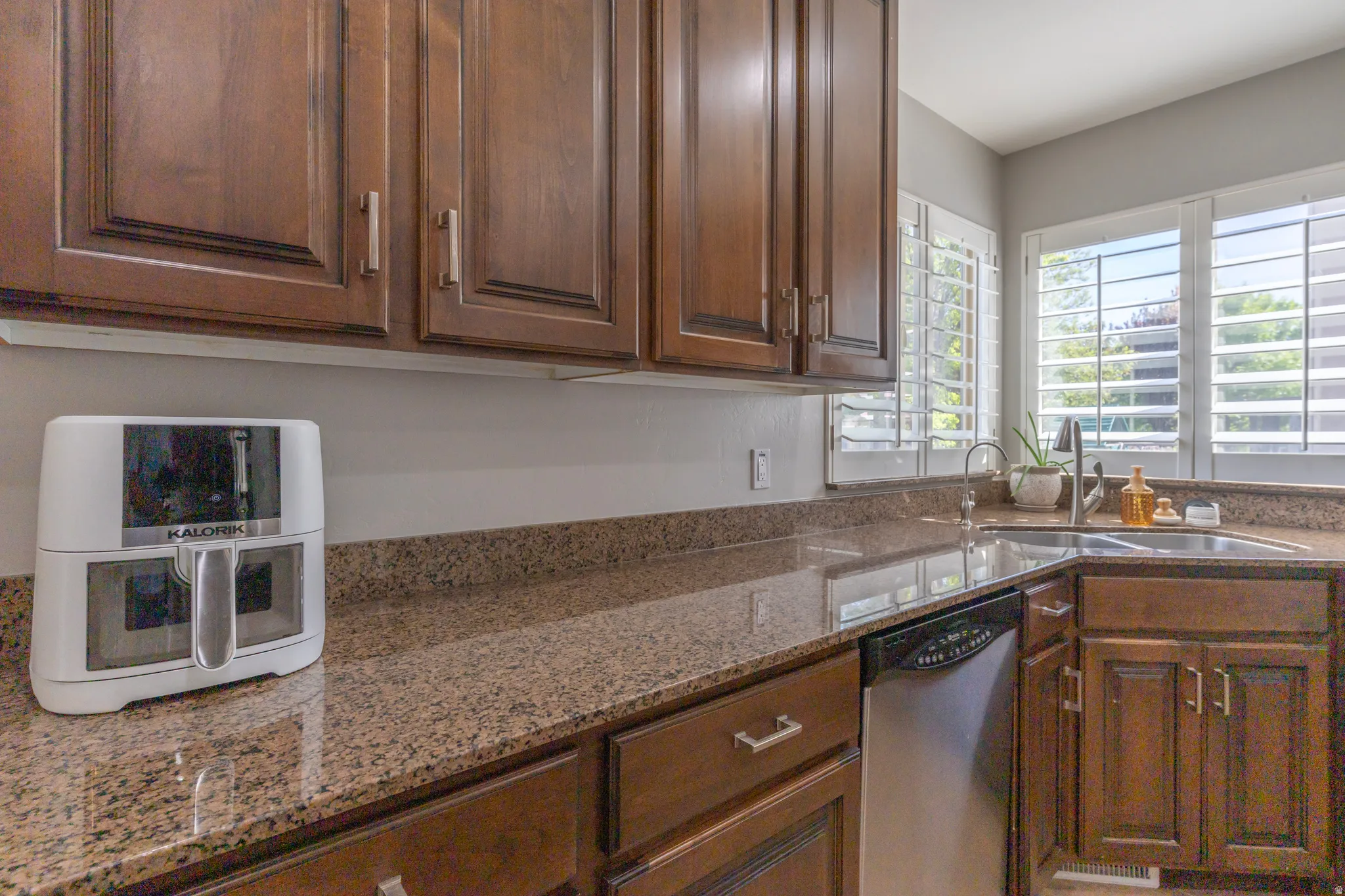 Kitchen featuring dishwasher and light stone counters