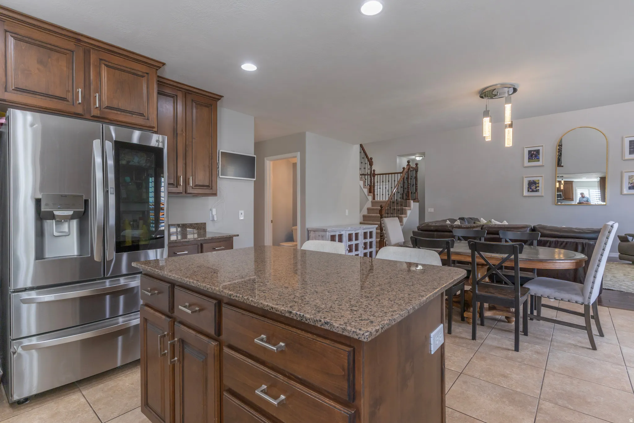 Kitchen featuring stainless steel fridge with ice dispenser, a center island, dark stone counters, light tile patterned floors, and open floor plan