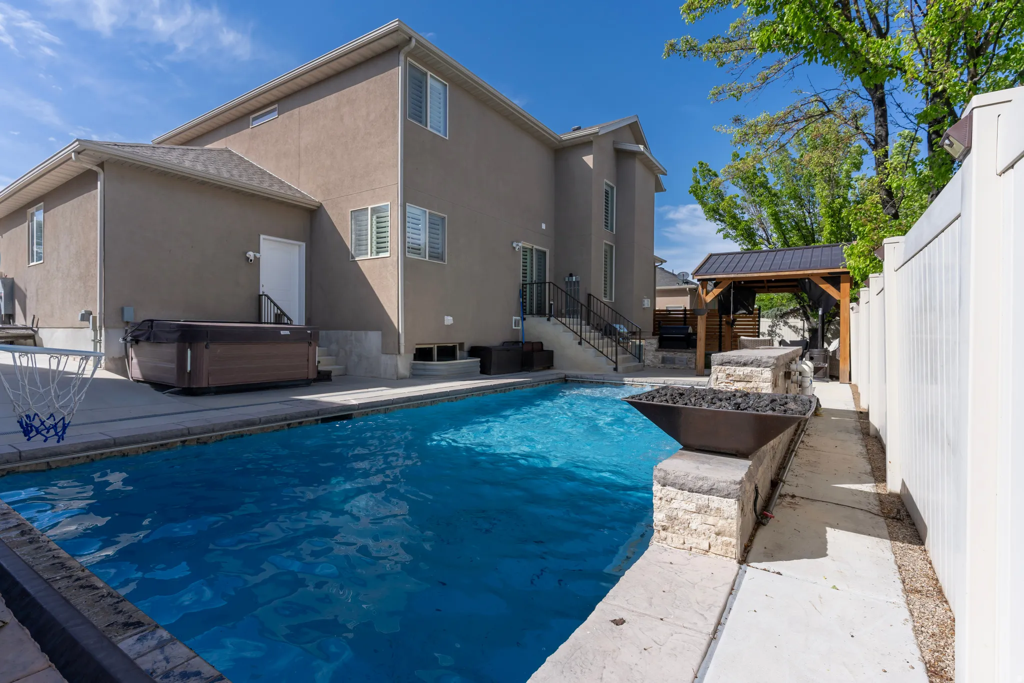 View of swimming pool featuring a hot tub, patio surround, a fenced backyard, and a gazebo