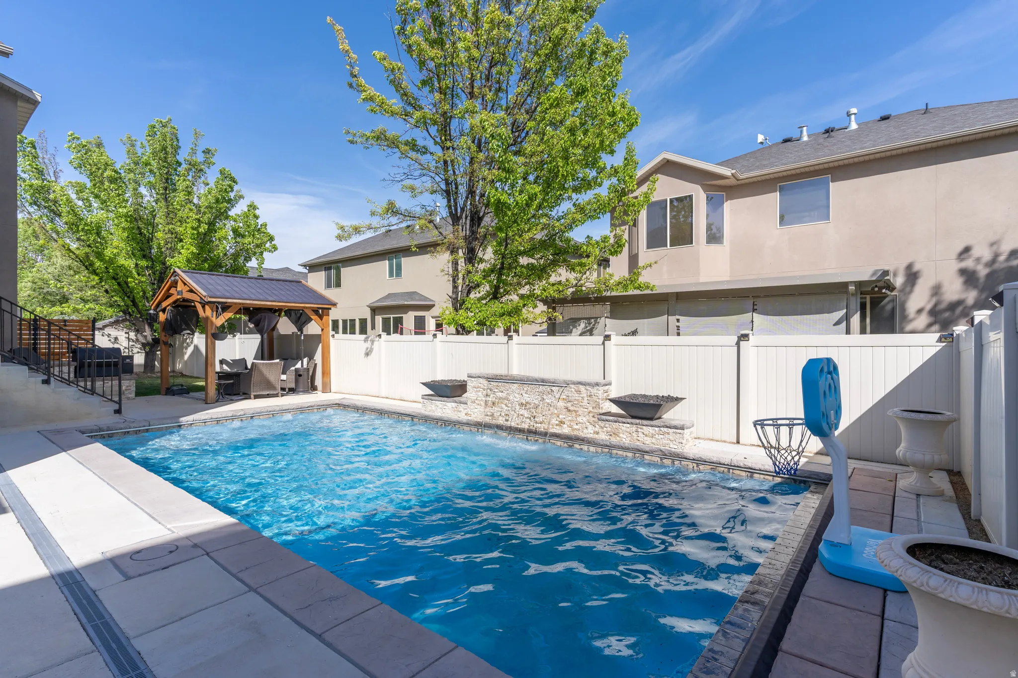 View of pool featuring patio surround, a fenced backyard, and a gazebo