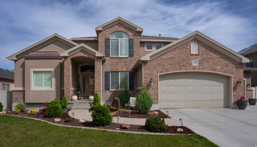 View of front of home featuring a garage, driveway, brick siding, and a front lawn