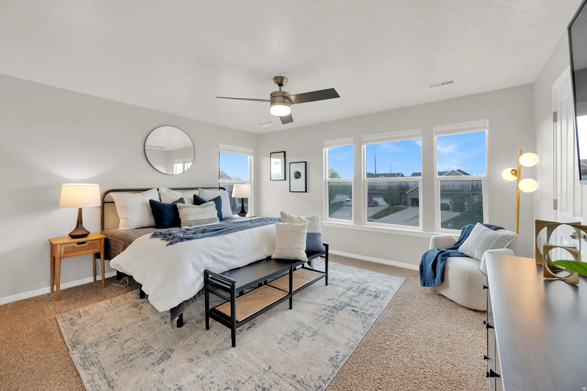 Primary Bedroom with light colored carpet and a ceiling fan and two walk-in closets