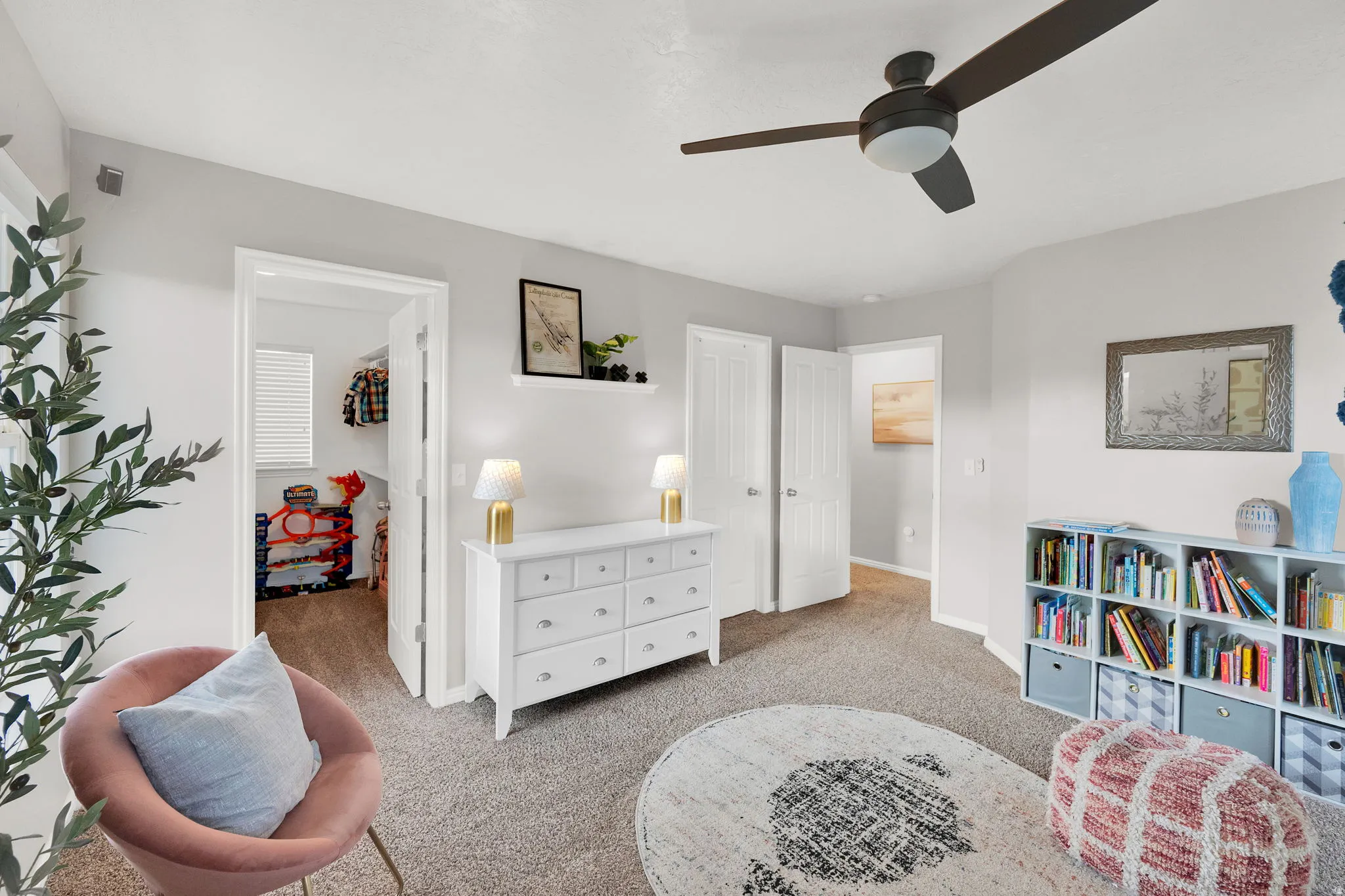 Sitting room featuring light carpet and a ceiling fan and entrance to bathroom and large walk-in closet