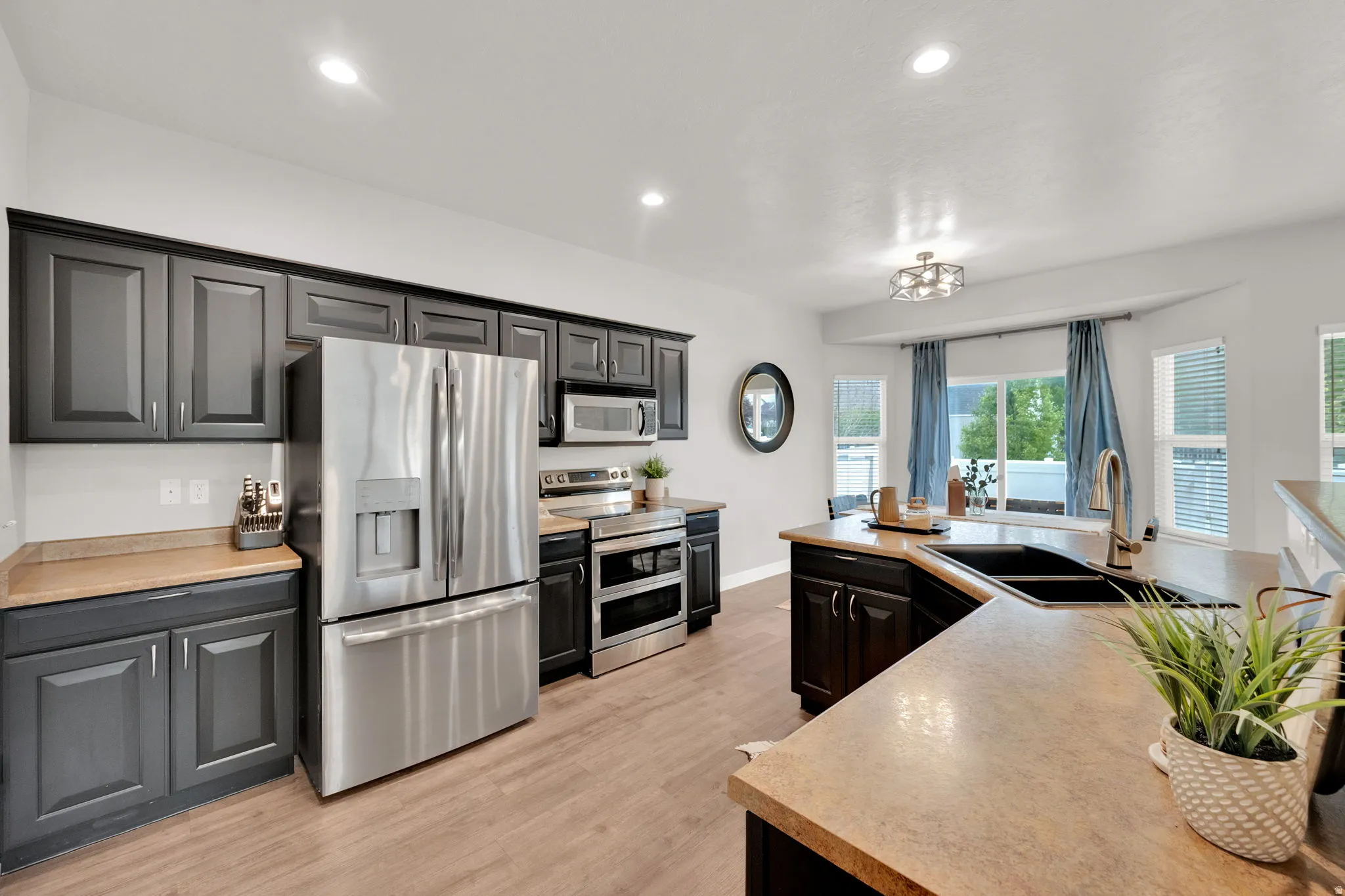 Kitchen with stainless steel appliances, light countertops, light wood-style flooring, and recessed lighting