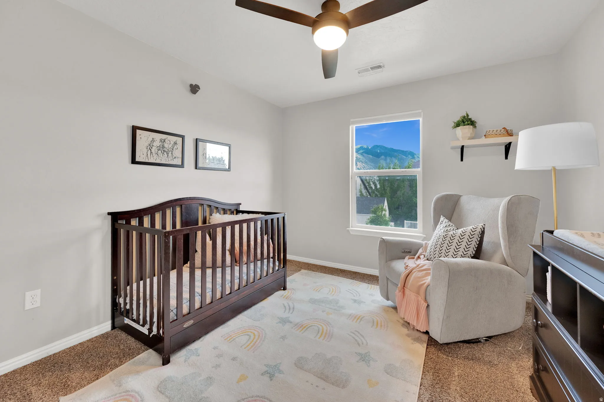 Bedroom with a nursery area, ceiling fan, and carpet floors