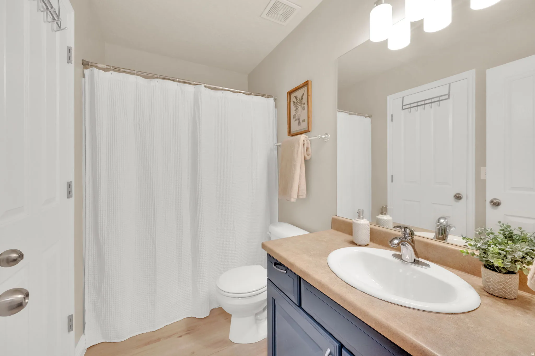Full bathroom with vanity, a shower with shower curtain, and light wood-type flooring