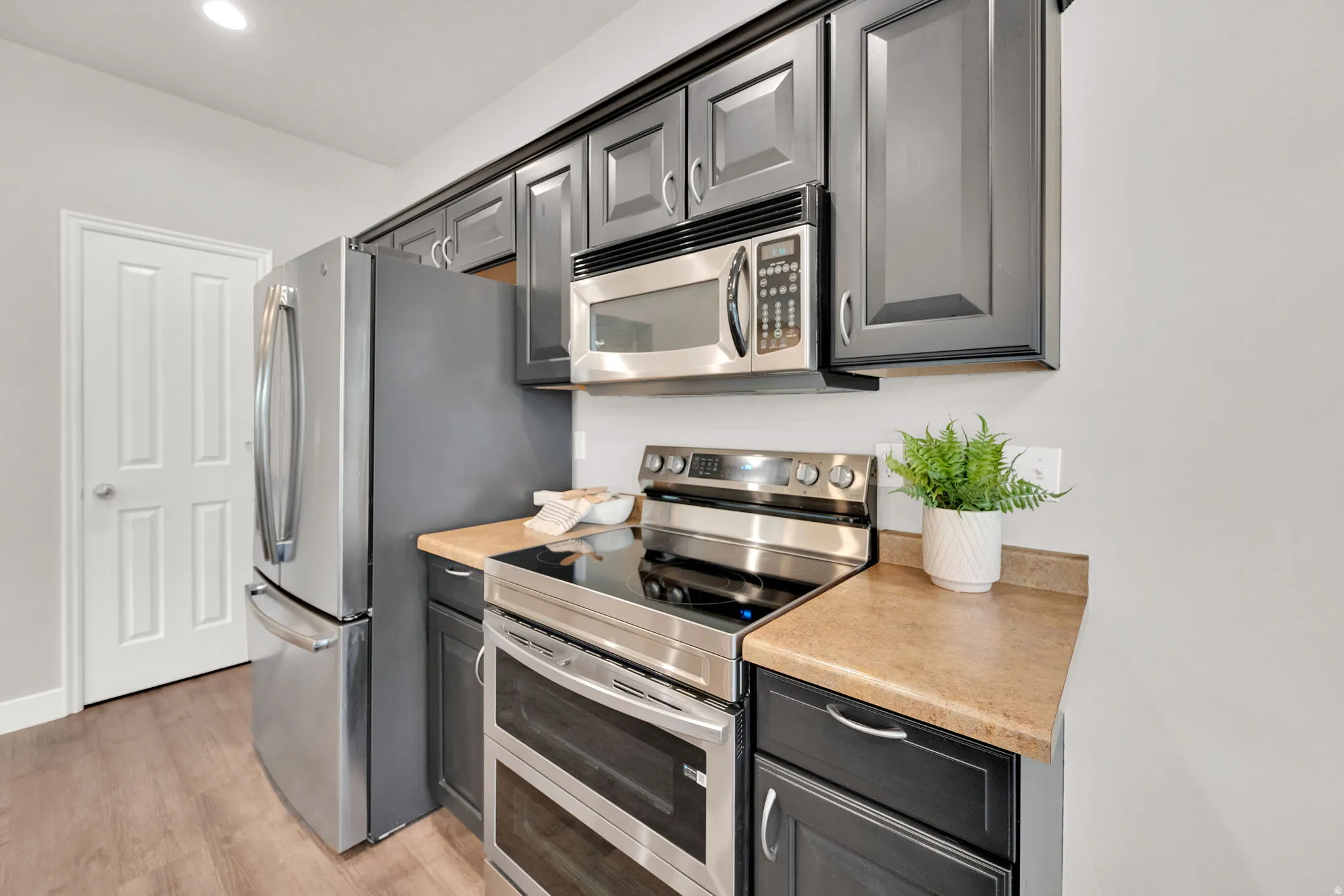 Kitchen with stainless steel appliances, light countertops, light wood finished floors, and gray cabinetry