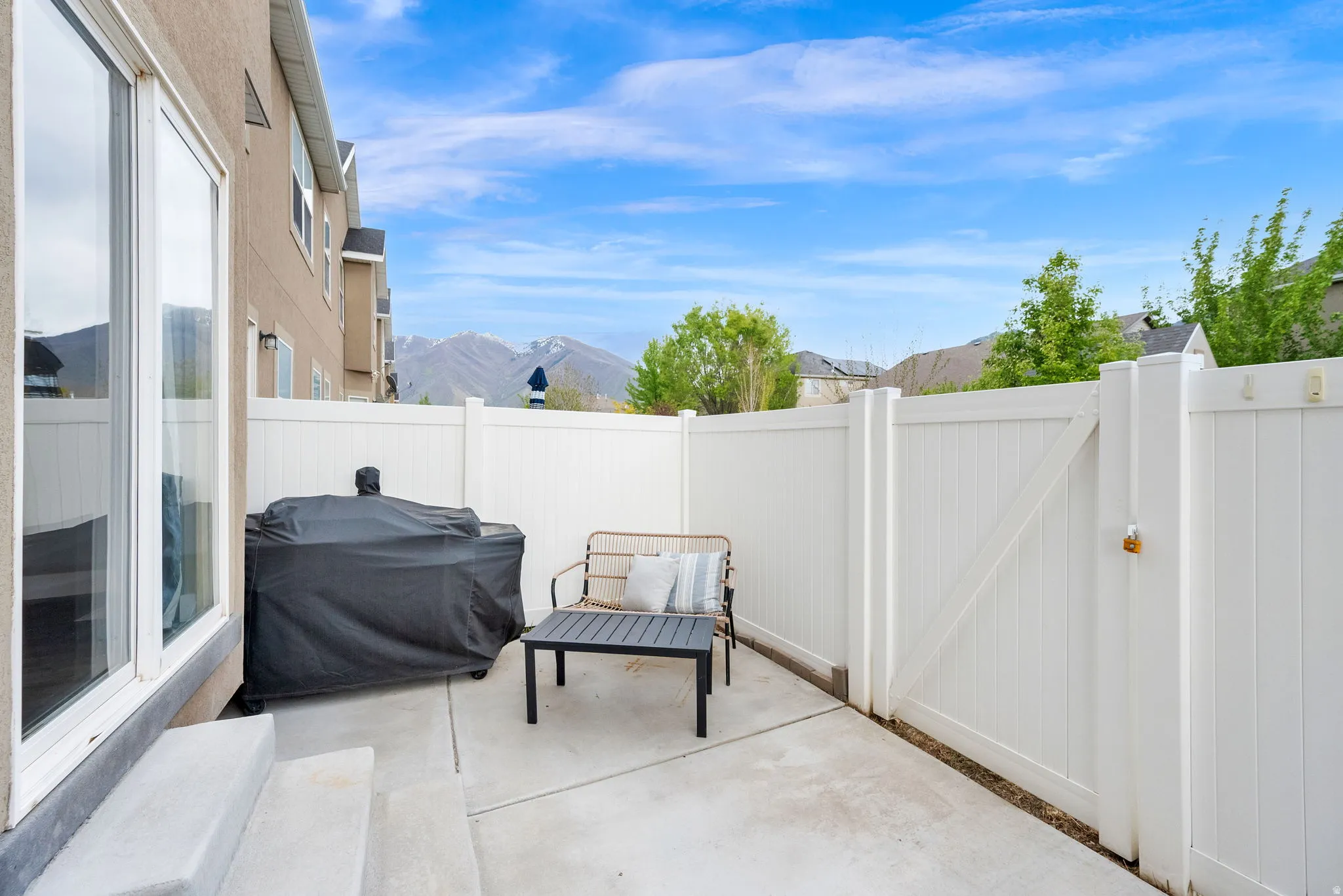 Fenced backyard with grilling area, a patio area, a gate, and a mountain view