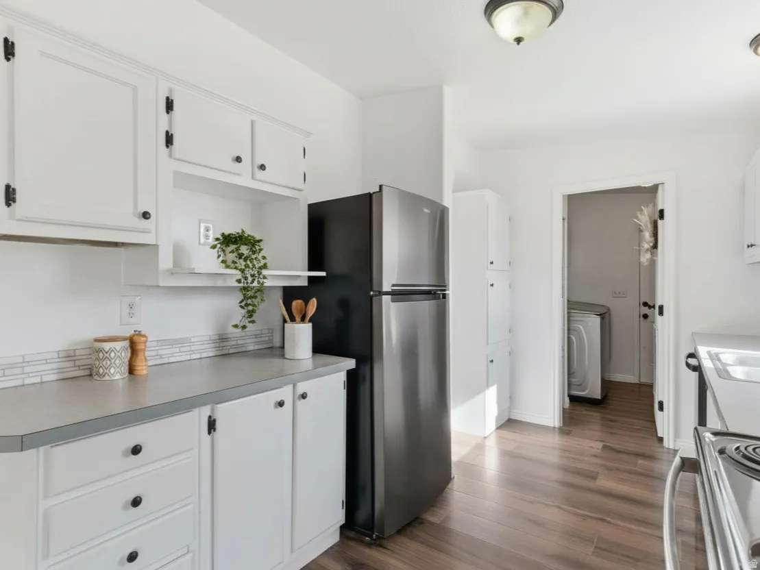 Kitchen with white cabinets, dark wood-style floors, stainless steel appliances, and light countertops