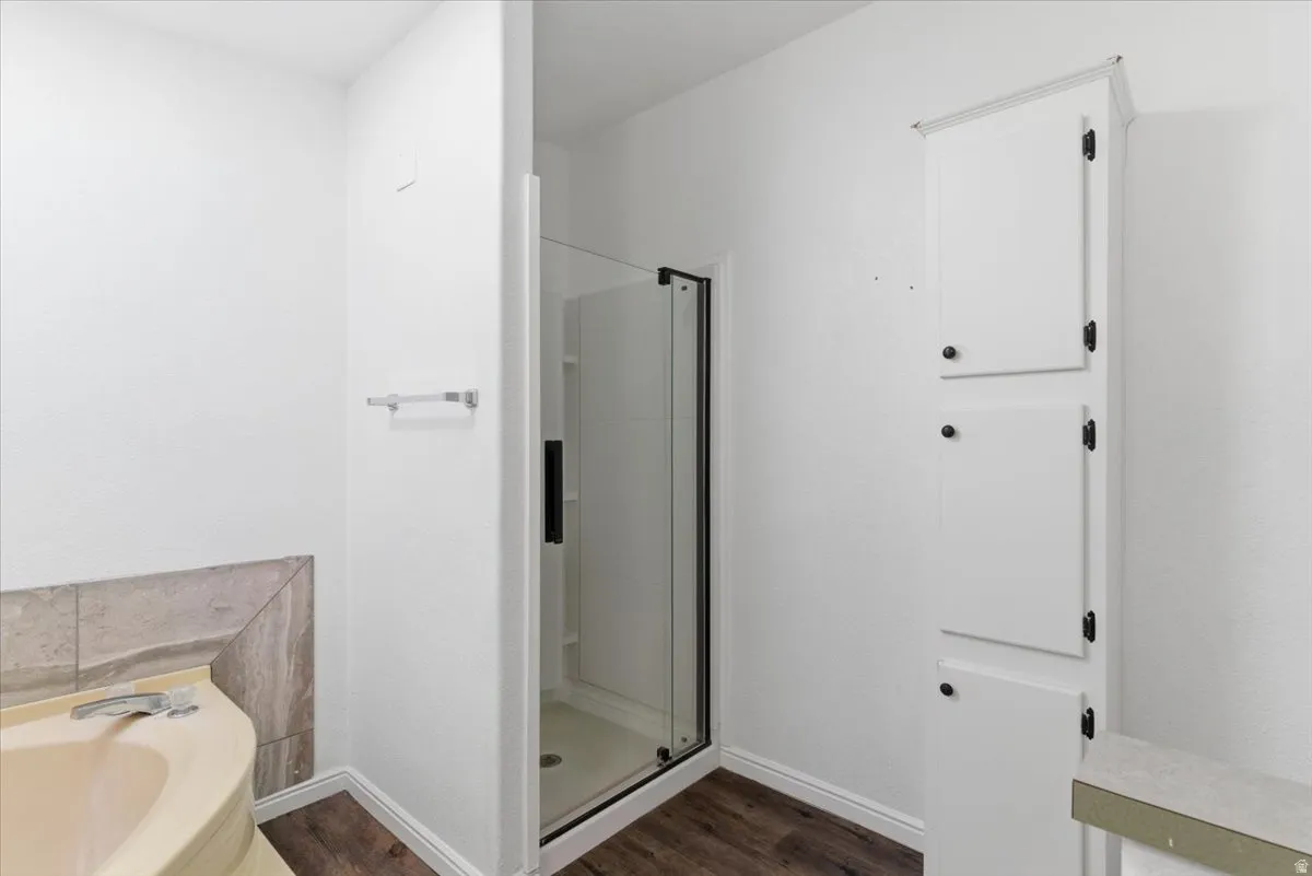 Full bathroom featuring a stall shower, a garden tub, and dark wood-type flooring